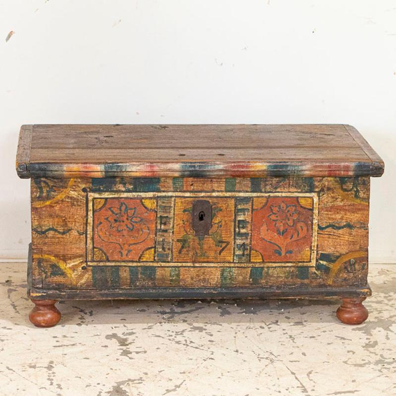 The original paint has aged gracefully in this lovely flat top trunk from Germany. The colors of red, teal and yellow create the traditional panel of flowers and trim along the top and bottom edges. The top has been worn to a warm and inviting