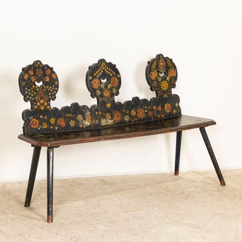 This delightful bench still maintains its original paint, with a lively array of flowers and flourishes in the traditional folk art style of the era. Look closely, as the bench has black paint over dark blue undertones, giving an overall impression