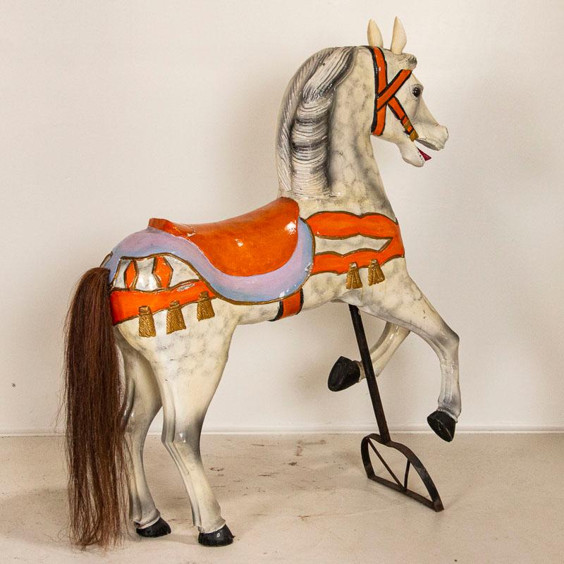 Whimsy and delight of an age gone by exude from this wonderful old carved Tivoli horse from Denmark. The original orange paint adds a bright air to the dapple gray of the carousel horse who still sports a genuine horse hair tail. Please examine the