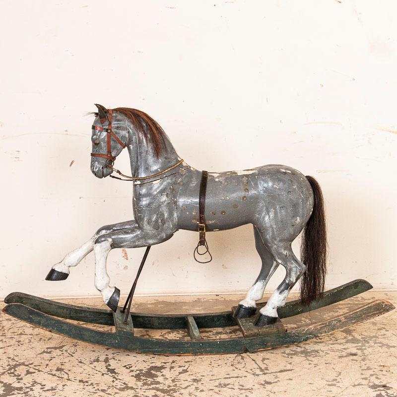 Everything about this endearing old rocking horse reminds one of childhood delights. This carved rocking horse originally was quite the expensive toy for some fortunate child of a well-to-do family. The original gray paint remains, along with aged