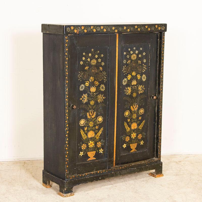 While you can frequently still find antique pine cabinets, it is difficult to find a sideboard with original folk art paint such as this one. The two panel doors are painted with a delightful yellow flower motif against a dark blue background which
