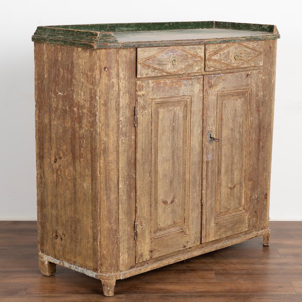 It is the original painted finish which has been scraped that brings out the warm patina of the pine in this lovely Gustavian sideboard from Sweden. 
The original green painted top provides a pop of color and great contrast to the base below.
The
