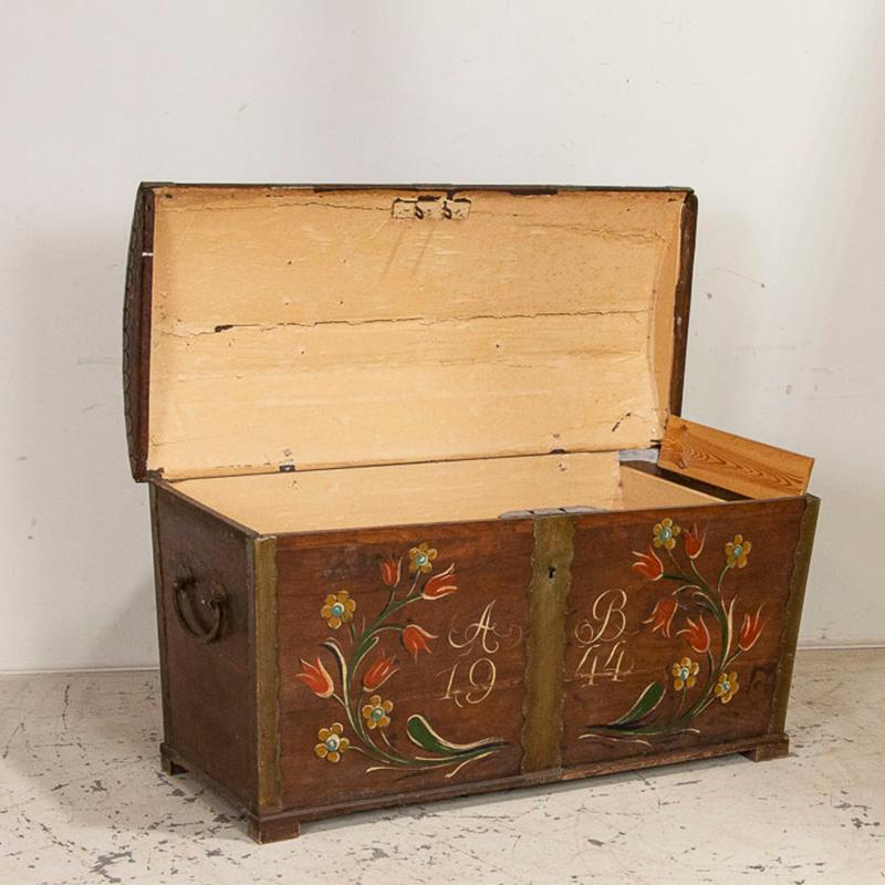This wonderful domed top trunk still maintains the vibrant original paint from when it was created. The bright red tulips, yellow flowers and green vines add a light-hearted grace to the large trunk. Notice the monogram of A & B, dated 1944? This