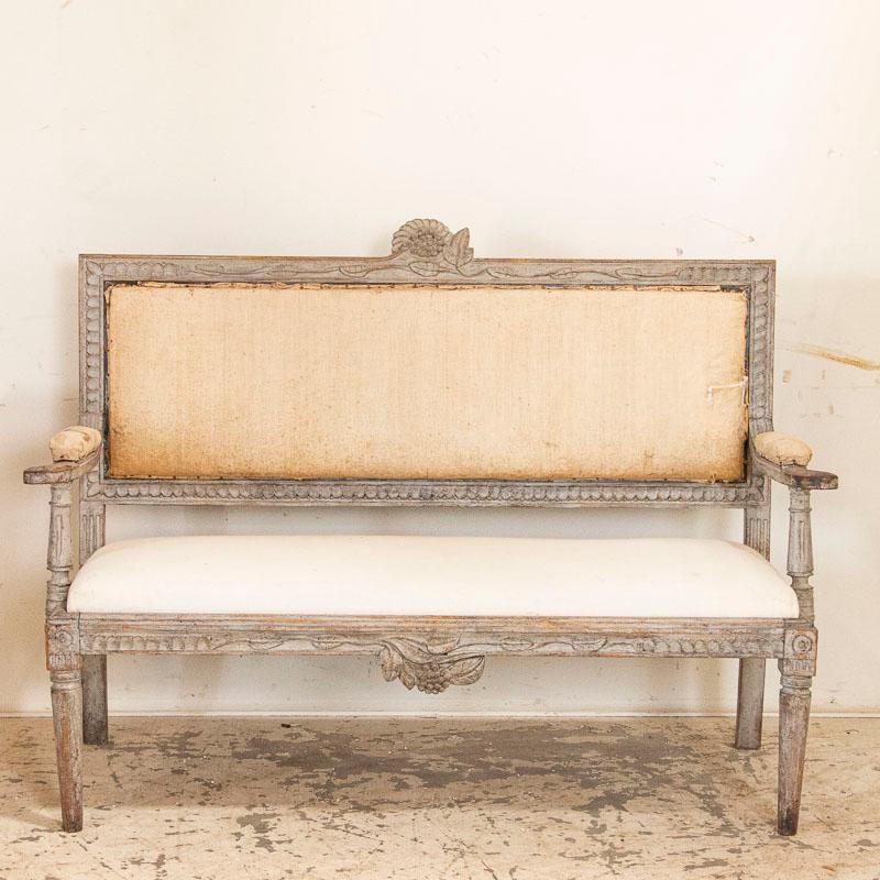 It is the soft, dove gray paint that has been rubbed and distressed over time that adds both character and grace to this lovely Gustavian settee or bench from Sweden. Notice the hand carved details that add a romantic touch to the bench as well. The