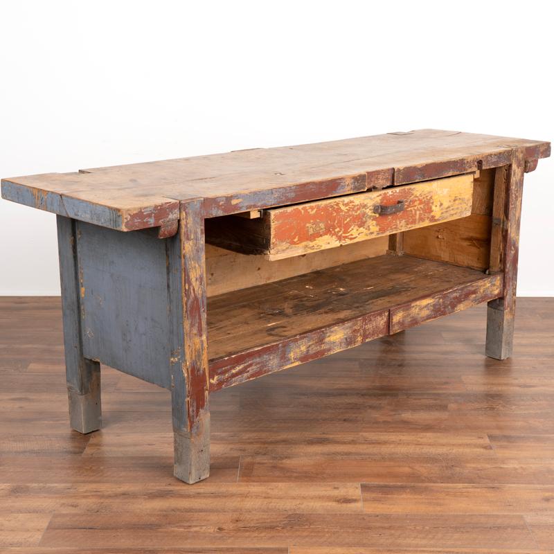 The worn patina of the original brick red and gray paint now reveal the pine below, reflecting generations of use in this wonderful work table. Loaded with character, notice how the multiple scratches, dings, cracks and stains all add to the vintage