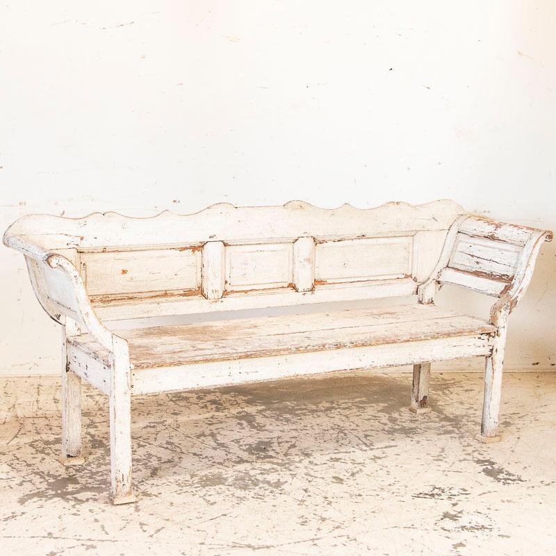 There is something endearing about simple country benches that have past the test of time, such as this delightful original white painted bench. The curve of the arms sway outward, inviting one to sit and linger while the paneled back is graced with