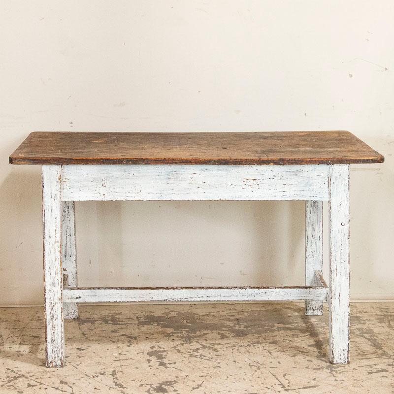 The white paint is all original on this old farm house table from Sweden. The many years of use are revealed in the wear and distress of the white paint, which adds to its true vintage appeal. The top was left natural pine, which has deepened to a