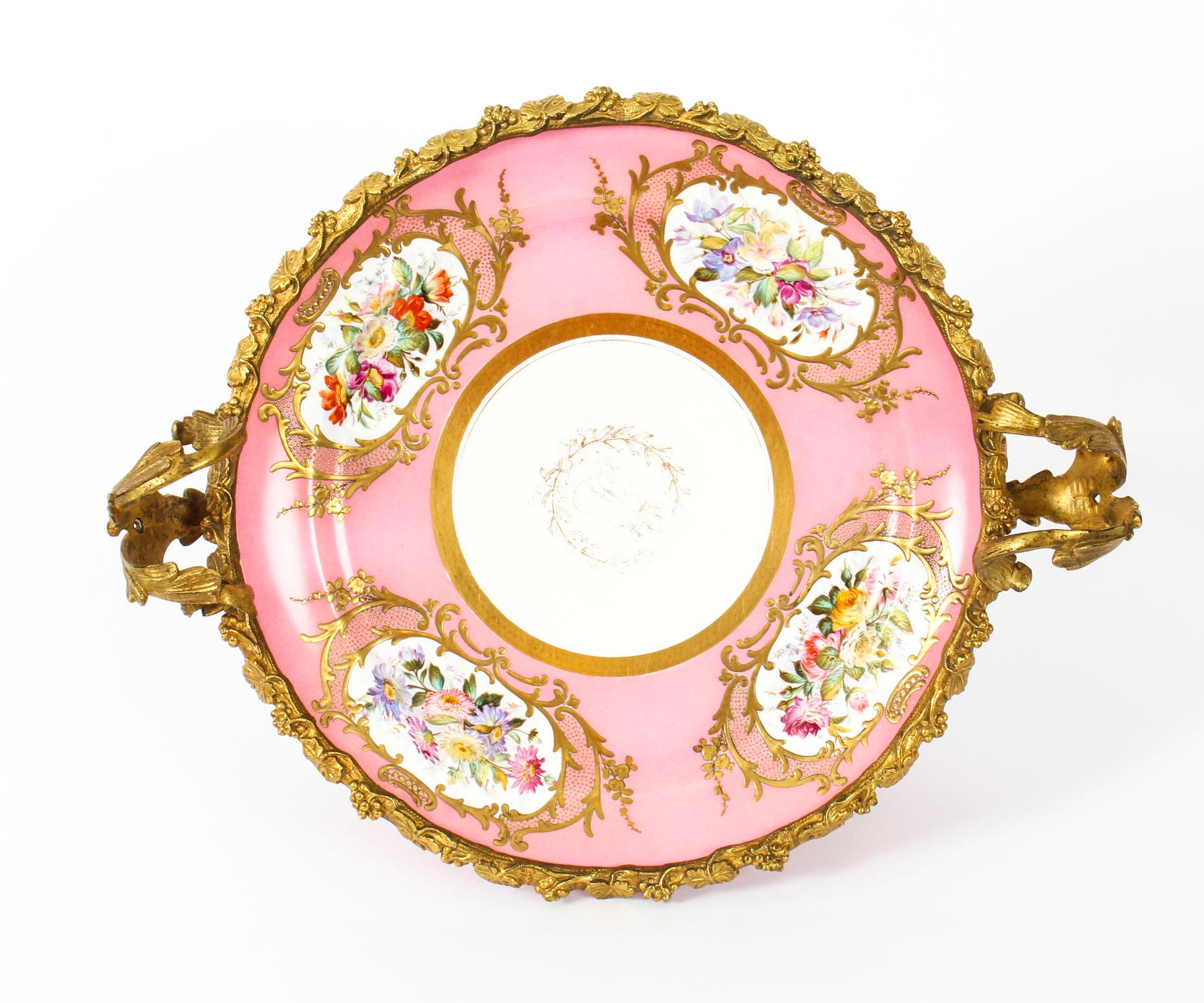 This is a stunning antique ormolu-mounted Sevres Chateau De Bizy porcelain centrepiece, with printed marks for 1843.
 
This striking centrepiece is round in shape with two elegant scrolling foliate ormolu handles and an exquisite ormolu border in