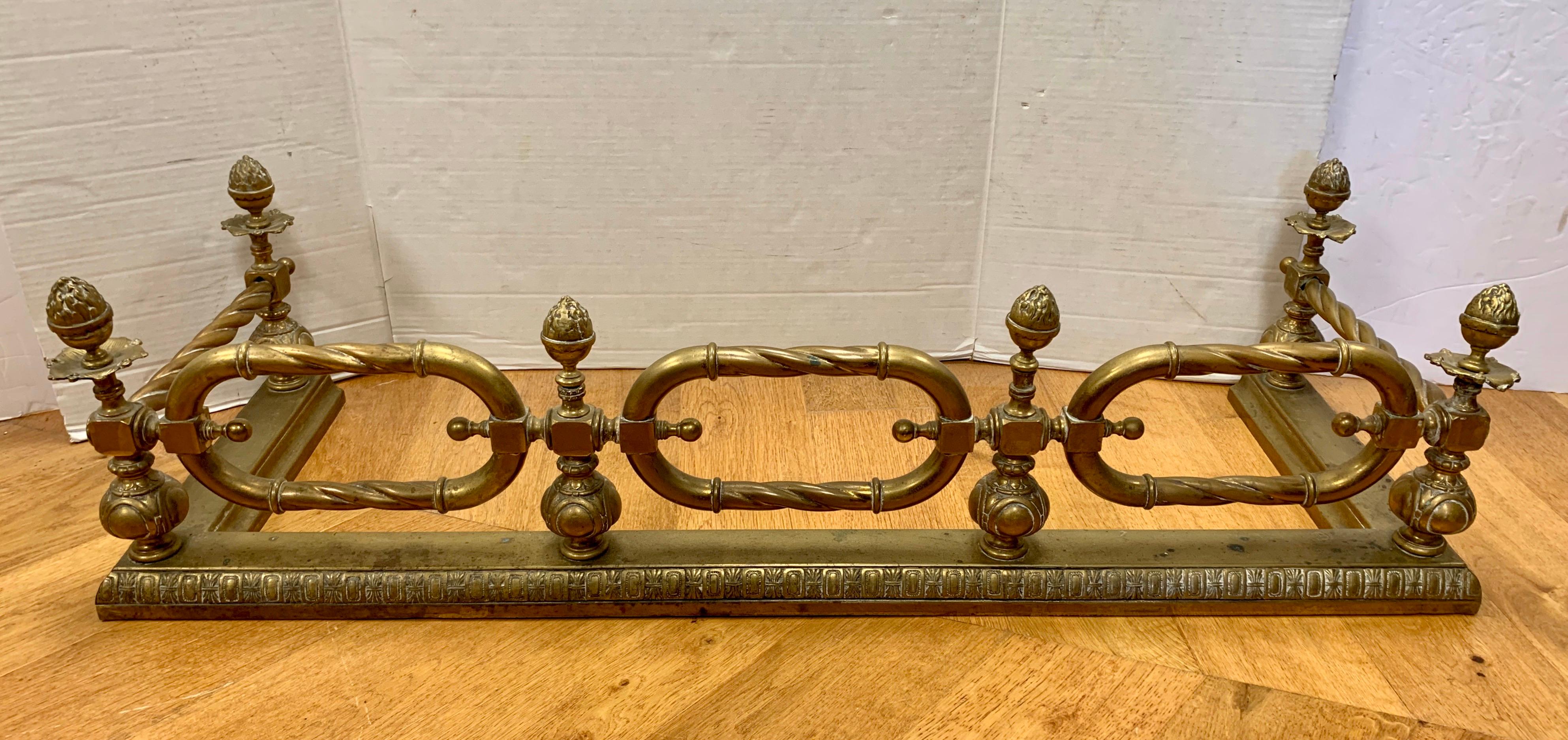 19th century very heavy brass fireplace fender resembles a large chain link of twisted brass with acorn finials in between.