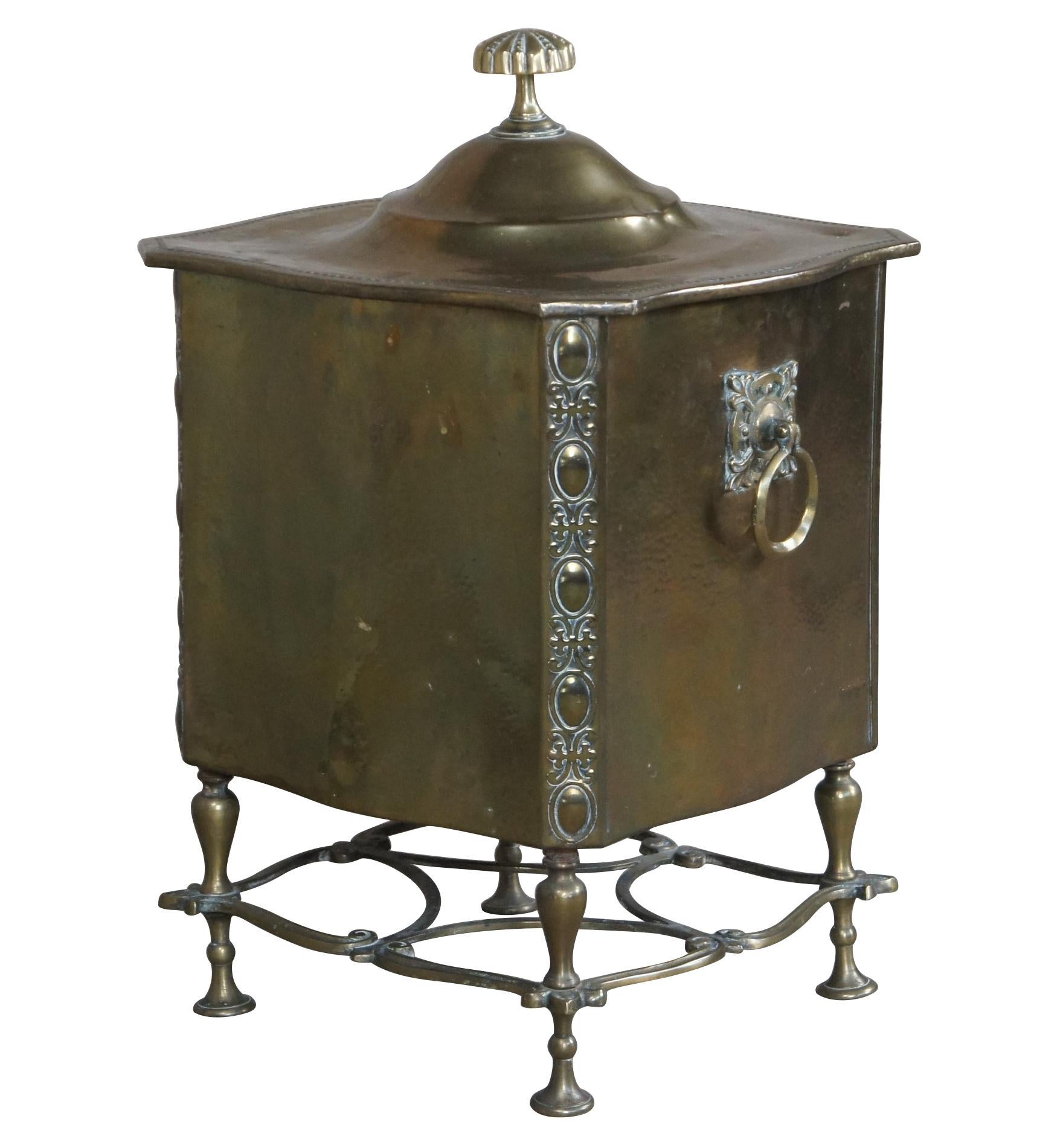 An ornate brass fireside bin.  Featuers a hammered finish with baroque motifs, knocker handles and trumpet footed base with diamond patterned trestle.  Could be used as a trash can, tobacco box or planter.  
