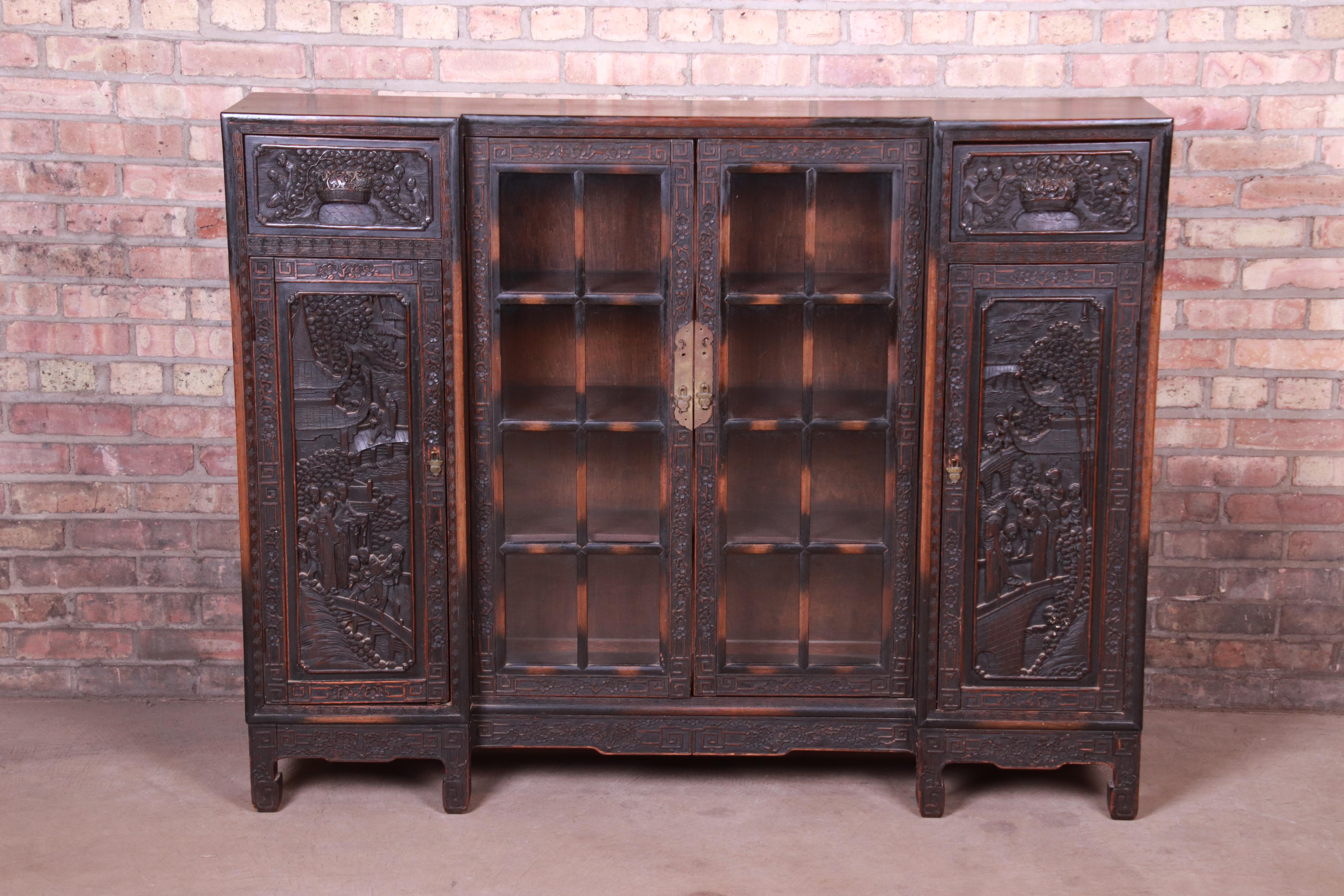 An exceptional antique Chinese Export carved bookcase

China, early 20th century

Ornate carved dark oak, with scenes depicted of a landscape with people and Chinese coins in relief to both sides. Original glass front doors.

Measures: 56.13