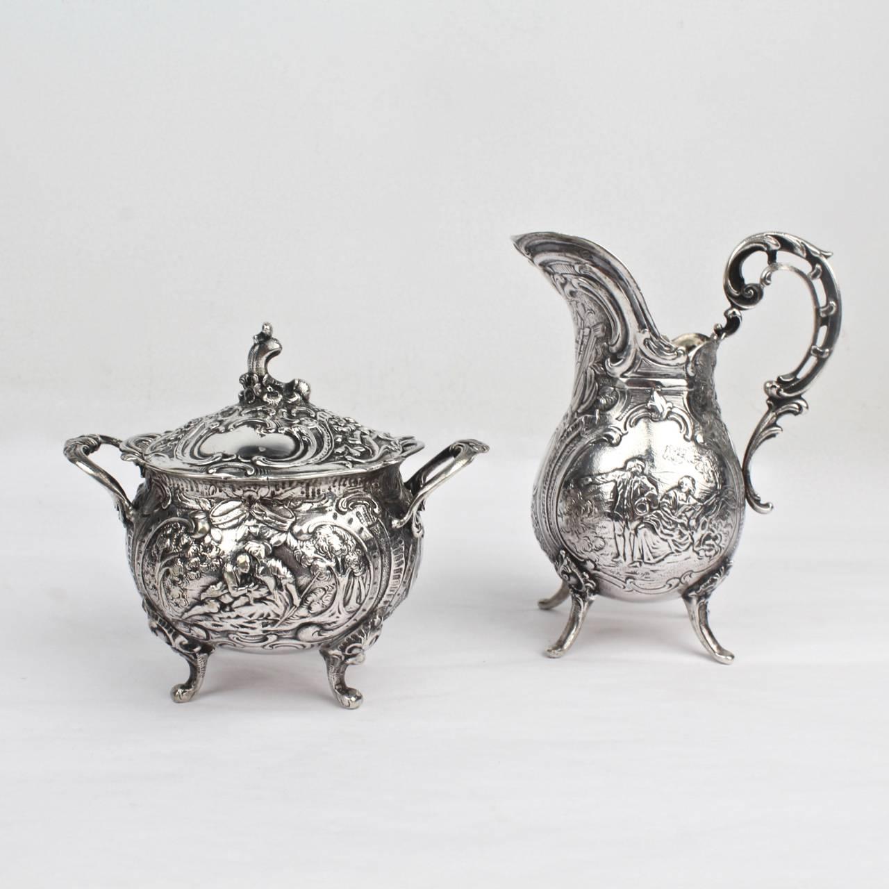 A highly ornate German solid silver creamer and sugar set by J. Riemann with repoussé decoration throughout.

Perfect for a small tea or coffee service (and of course the cabinet)!

The central cartouches on each piece depict pastoral scenes