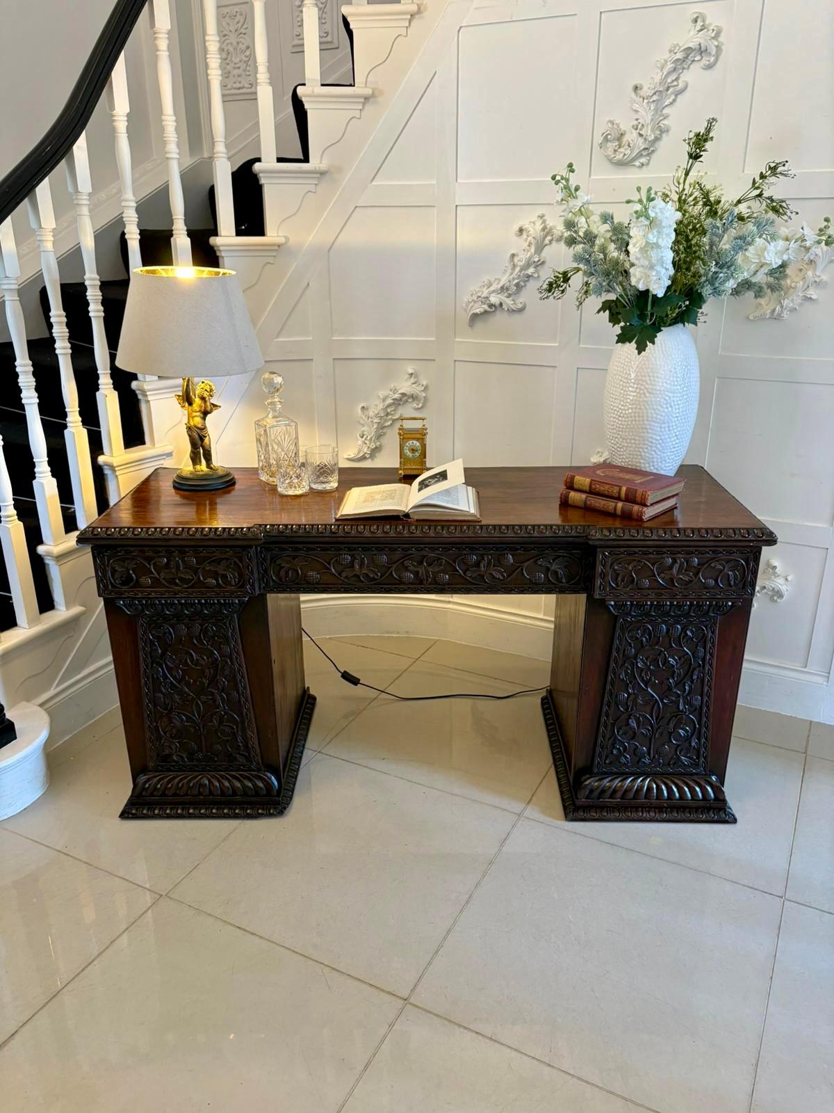 Antique ornate small carved Anglo-Indian padauk inverted breakfront pedestal sideboard having an inverted padauk top with an ornate carved edge above a large central carved fronted drawer flanked by two smaller drawers above two pedestals with