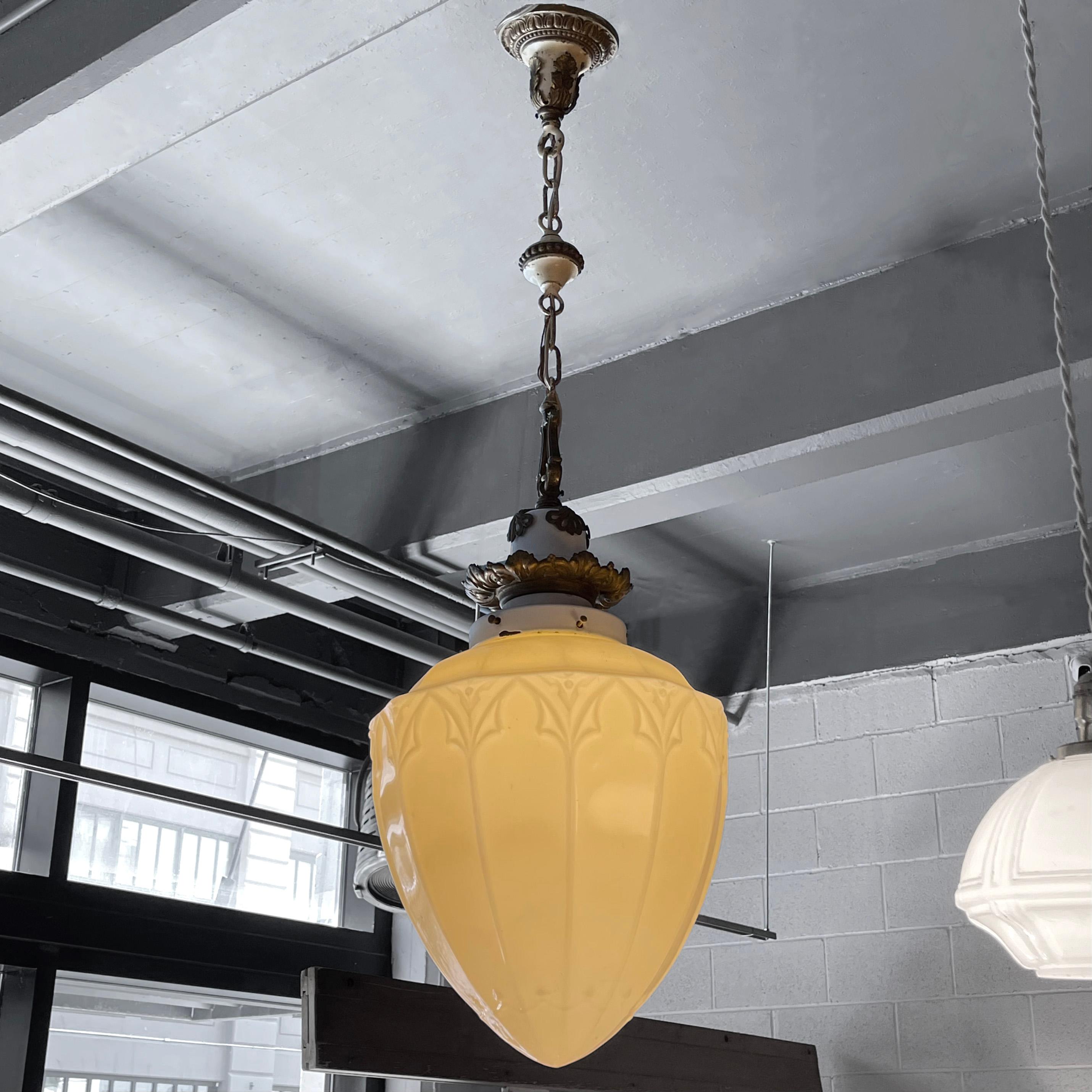 Early 20th century, Victorian, pendant light features a pressed vaseline glass shade with ornate, brass, filigree hardware with enamel accents. The pendant hangs at an overall height of 46 inches but can be adjusted. The height of the shade is 15