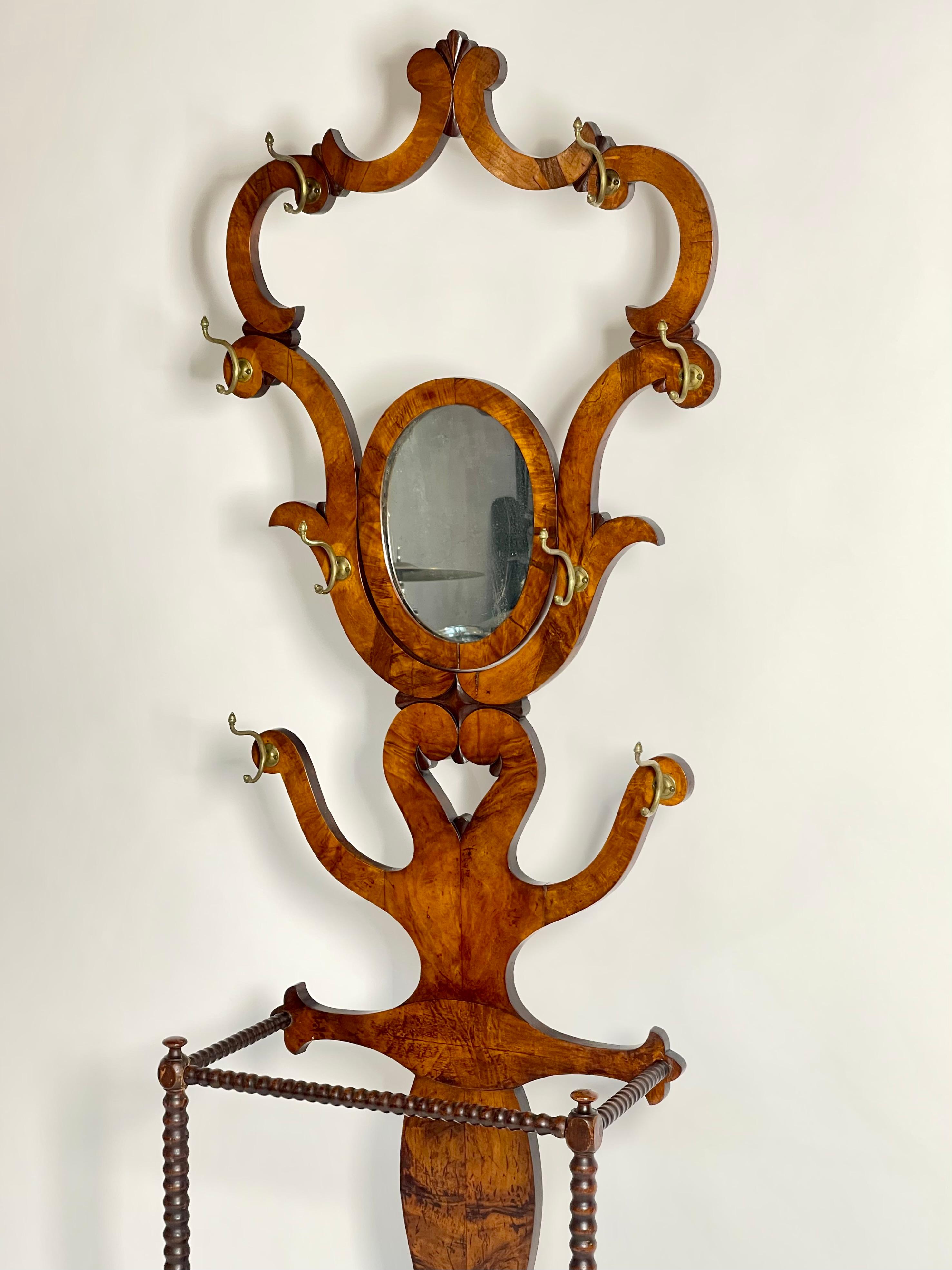 Antique Ornate Victorian Mahogany Hall Tree:
With oval swivel mirror, metal lined umbrella valet and patina’d bronze hooks, original flathead brass screws. 

A stunning example of scrollwork and veneer selection. A perfect piece for a classical