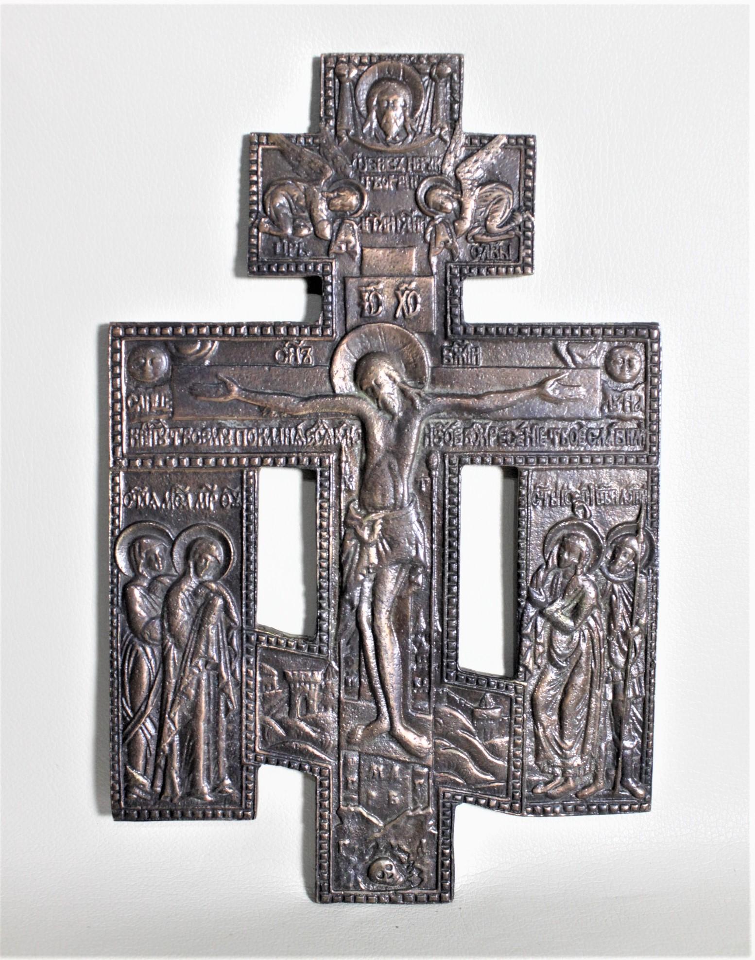 This antique cast and patinated bronze cross is unsigned, but presumed to have been made in Russia or the Ukraine in circa 1890 in the period Victorian style. This cross or crucifix is quite ornately cast with Jesus on the cross with the apostles