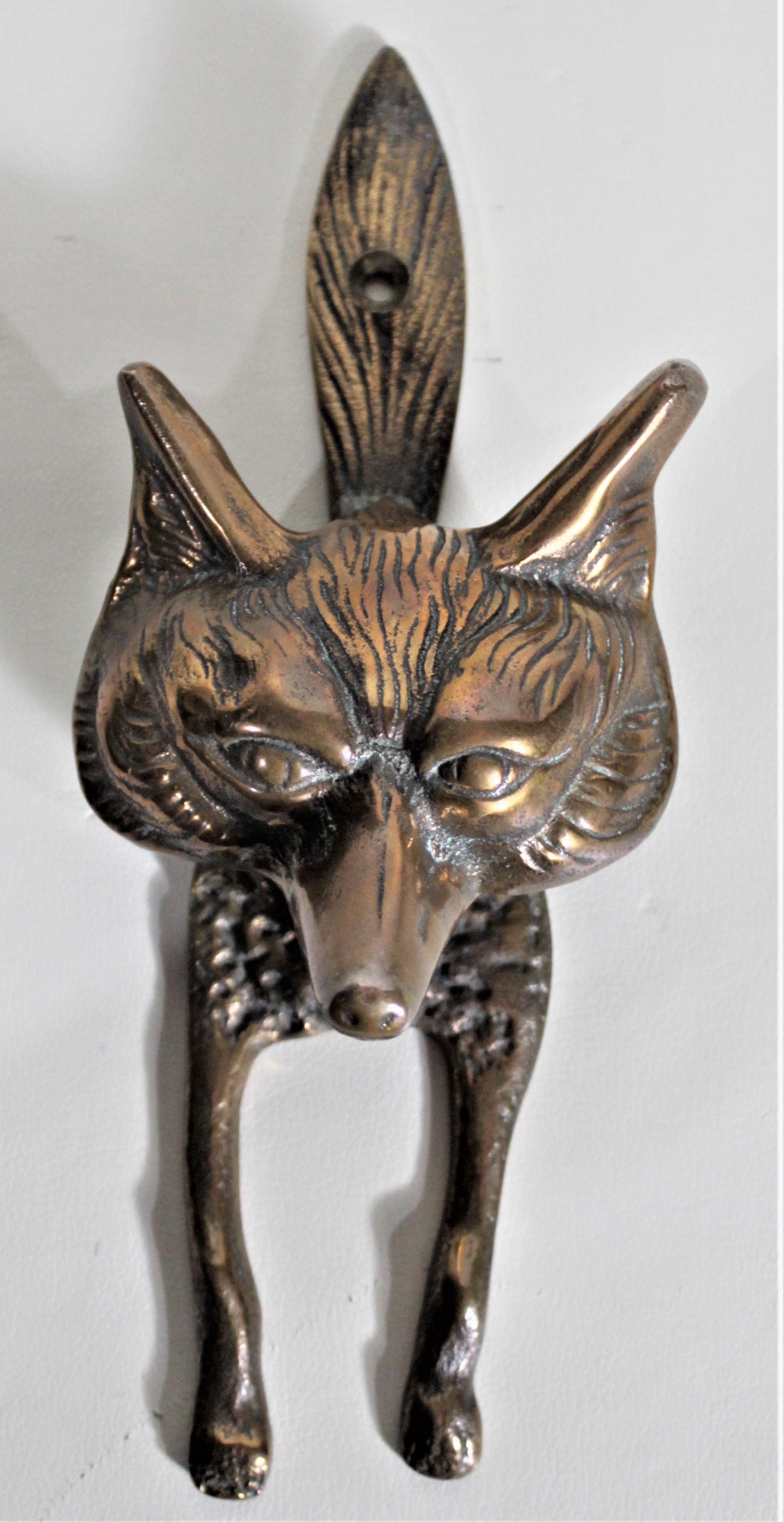 This ornately cast solid brass door knocker has no maker's marks, but presumed to have been made in likely Austria in circa 1920. This door knocker is fashioned as a stylized fox with the tail, torso and legs making up the base plate, and the head