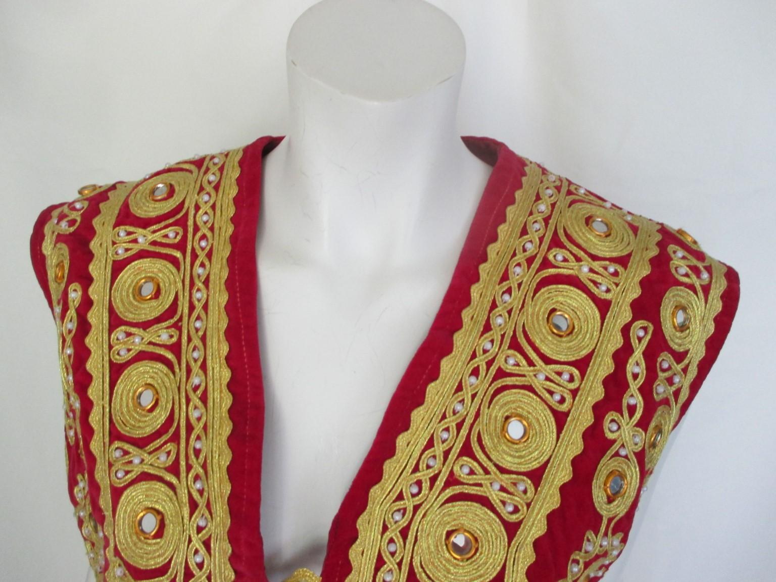 This is an unique antique ottoman vest, decorated with elaborate gold threads.

We offer more exclusive vintage items, view our frontstore.

Details:
Color and material: red velvet , gold embroidery with round mirrors
fully lined
3 buttons
2