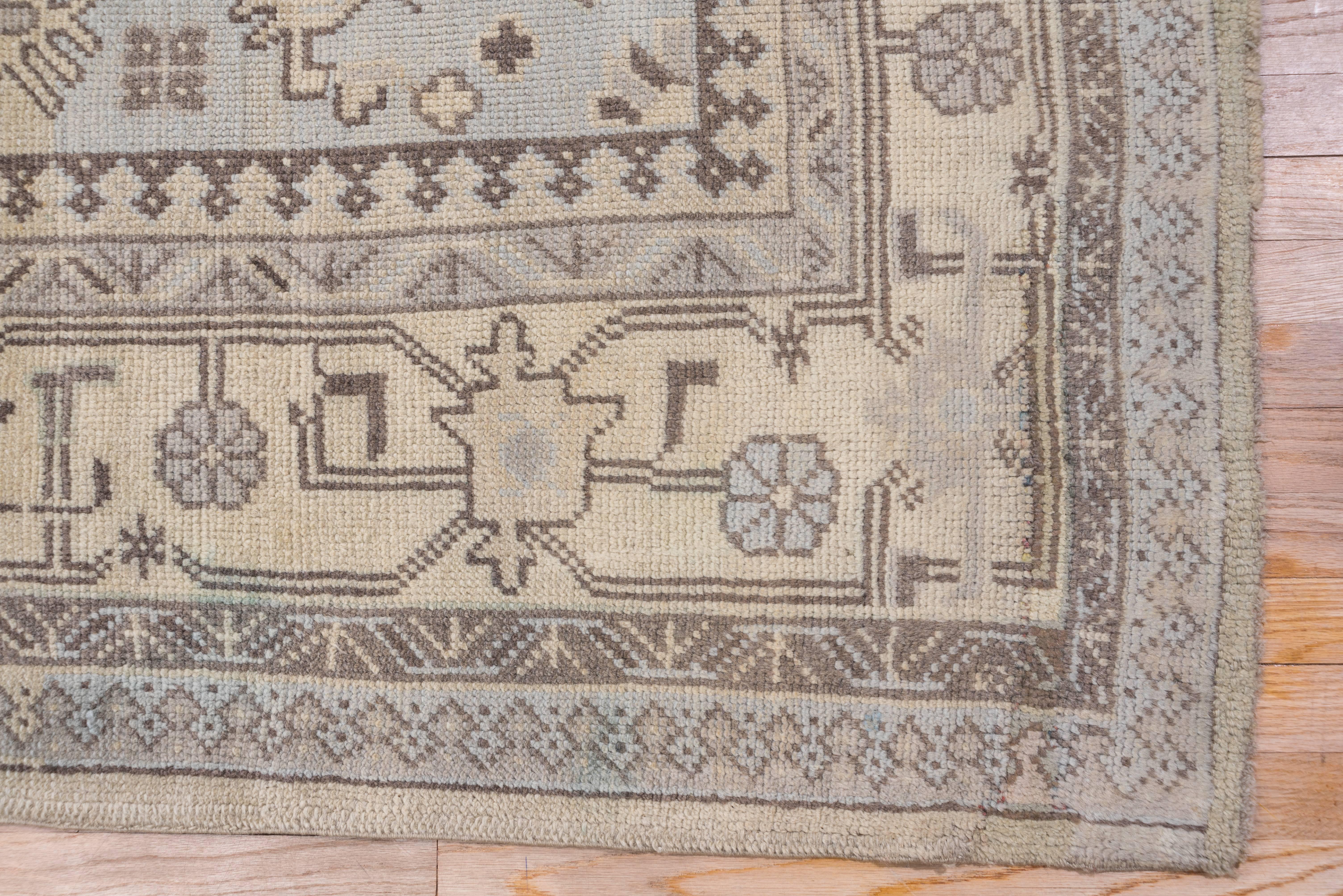 Here is a west Turkish workshop carpet with a stepped, pendanted medallion on a sandy ivory plain field set within stepped corners displaying detached geometric motives. The old ivory main border displays very skeletal turtle palmettes and lollipop