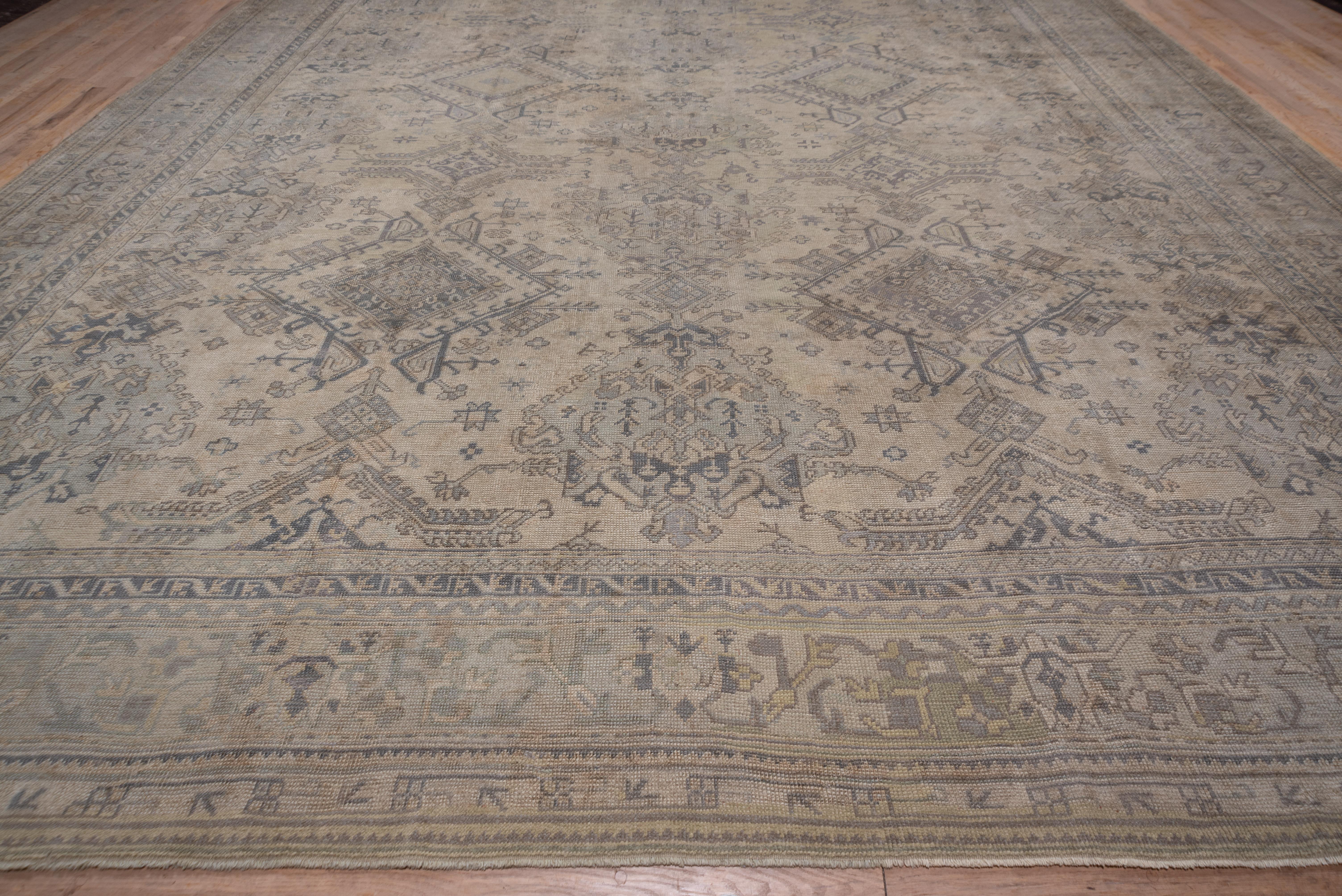 Au lieu du champ rouge habituel de la Turquie, ce tapis de Turquie occidentale à palmettes et à motifs colonnaires Yaprak présente un champ beige avec trois montants complets et deux montants fractionnés. De petites étoiles et d'autres ornements