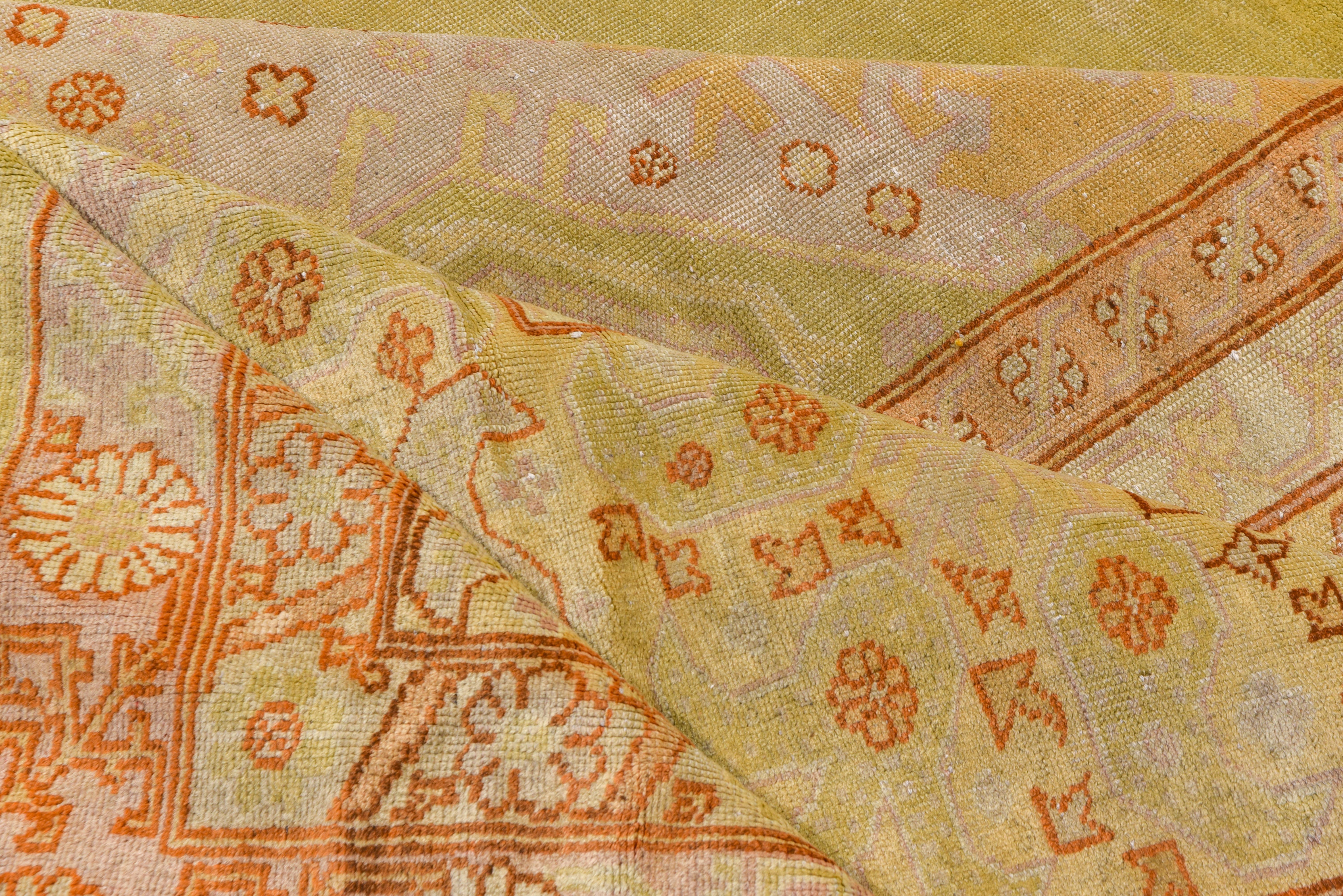 This generally soft-toned west Turkish square town carpet features an open grey-green field with an ivory medallion and corners. The sand main border shows bottehs and related flowers.