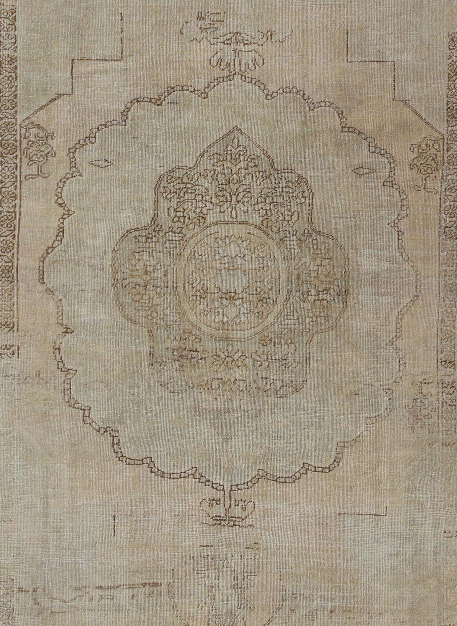 Mesures : 8'0'' x 12'1''

Ce tapis ancien en laine d'Oushak présente un médaillon superposé de grande taille avec des vignes et des fleurs détaillées. Un cadre de motifs floraux et de branches stylisées forme la bordure et complète l'esthétique de