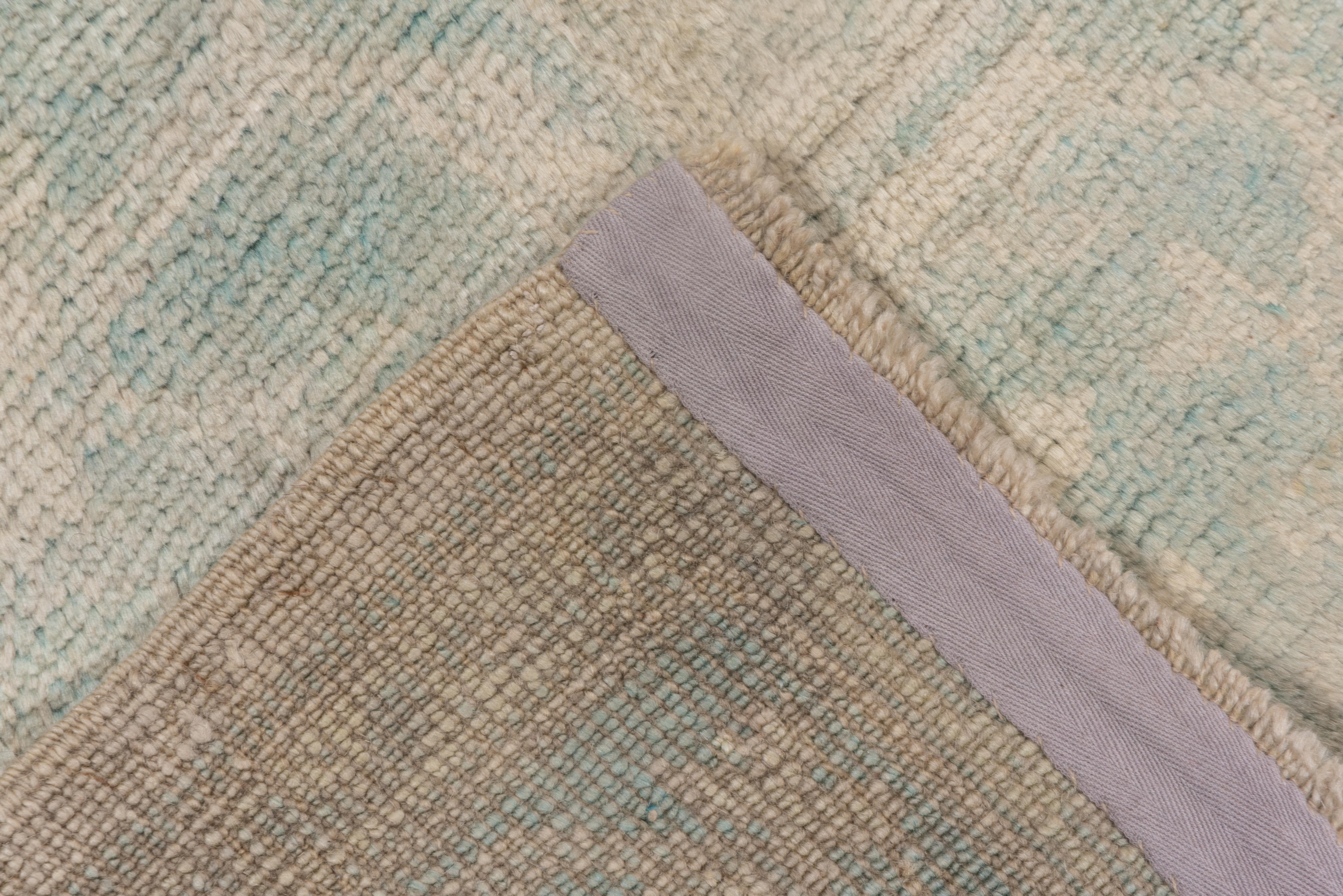 Ce tapis d'atelier d'Anatolie occidentale en bon état présente un champ beige-ivoire avec un motif symétrique de palmettes encadré par une bordure principale bleu pâle avec d'autres palmettes et des vrilles droites.
 
