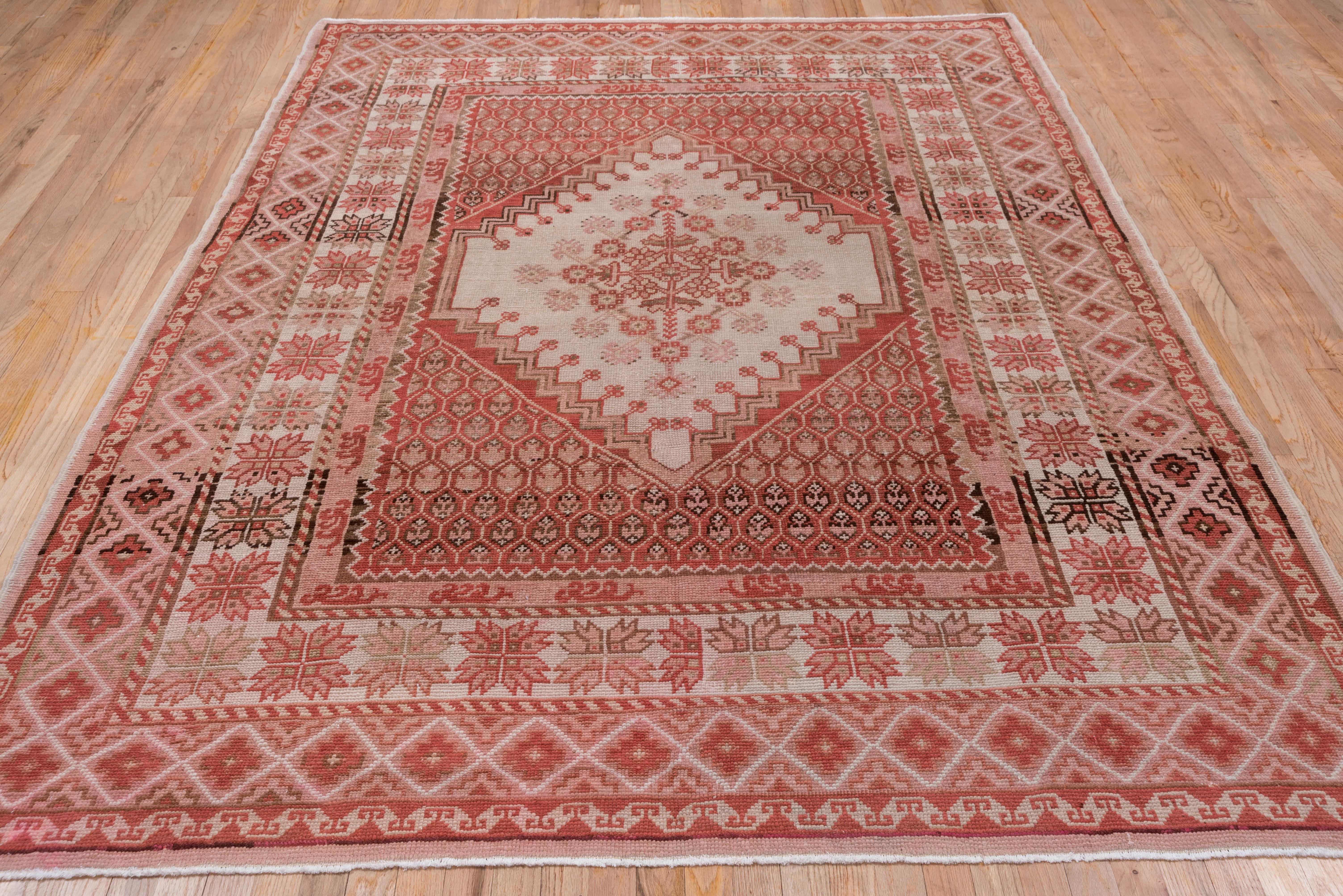 The old ivory sub-field displays a carnation and rosette skeletal medallion while the supporting brown field shows a mall hexagonal lattice pattern enclosing little flowers. The old ivory min border of this northwest Turkish carpet exhibits an