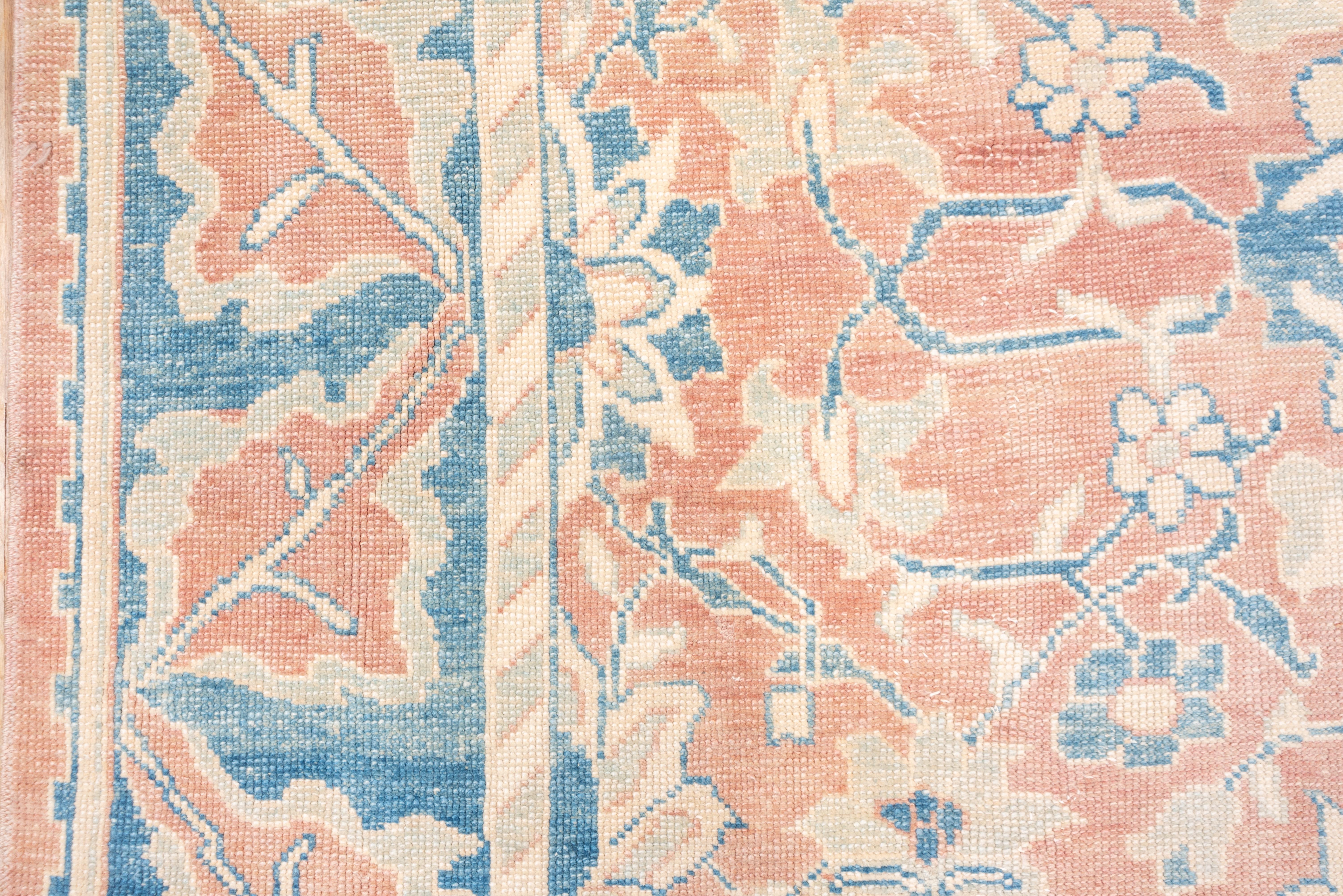 The light pink orange field of this west Anatolian carpet shows a centralized pattern of small palmettes, rosettes blue vinery and leaves, all around a small yellow center. Abrashed medium blue border with bold veined leaves.