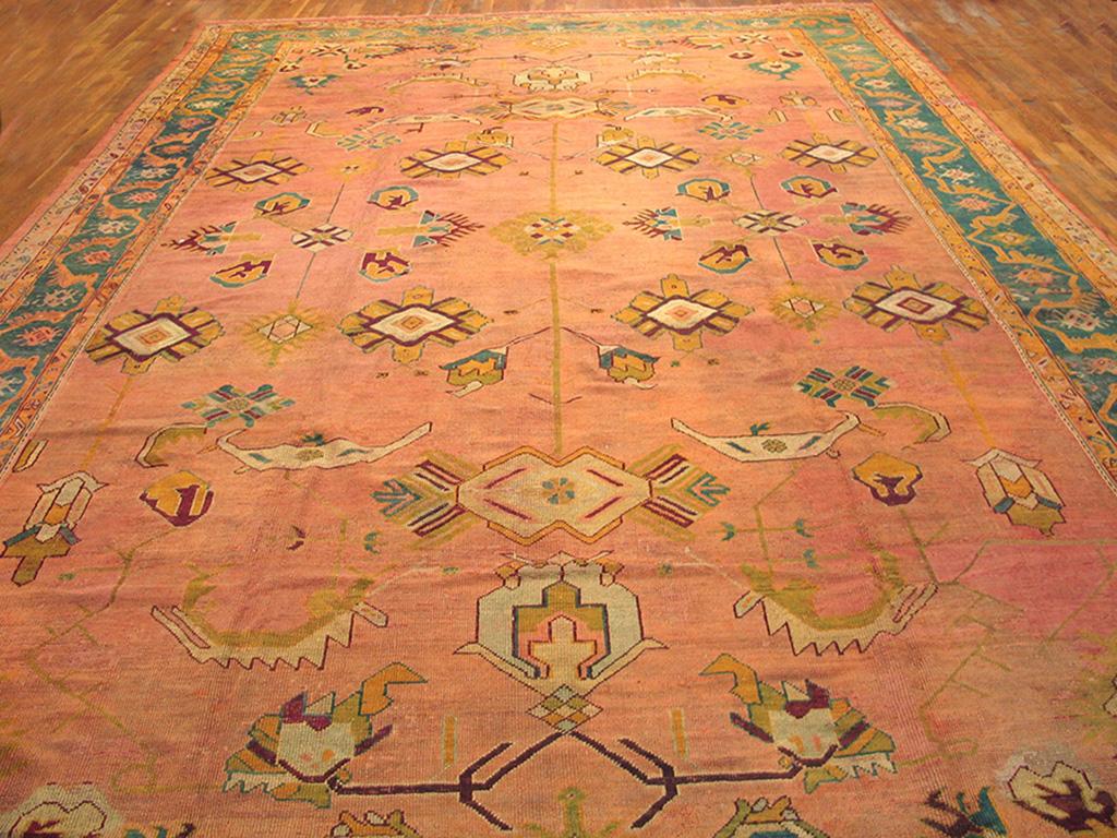 Peach and orange works only on Oushaks. Three explicit columns of small lozenges and geometric flowers and palmettes organize the spaciously drawn field of this west Anatolian carpet. The middle blue main border with a fringed arcading vine pattern