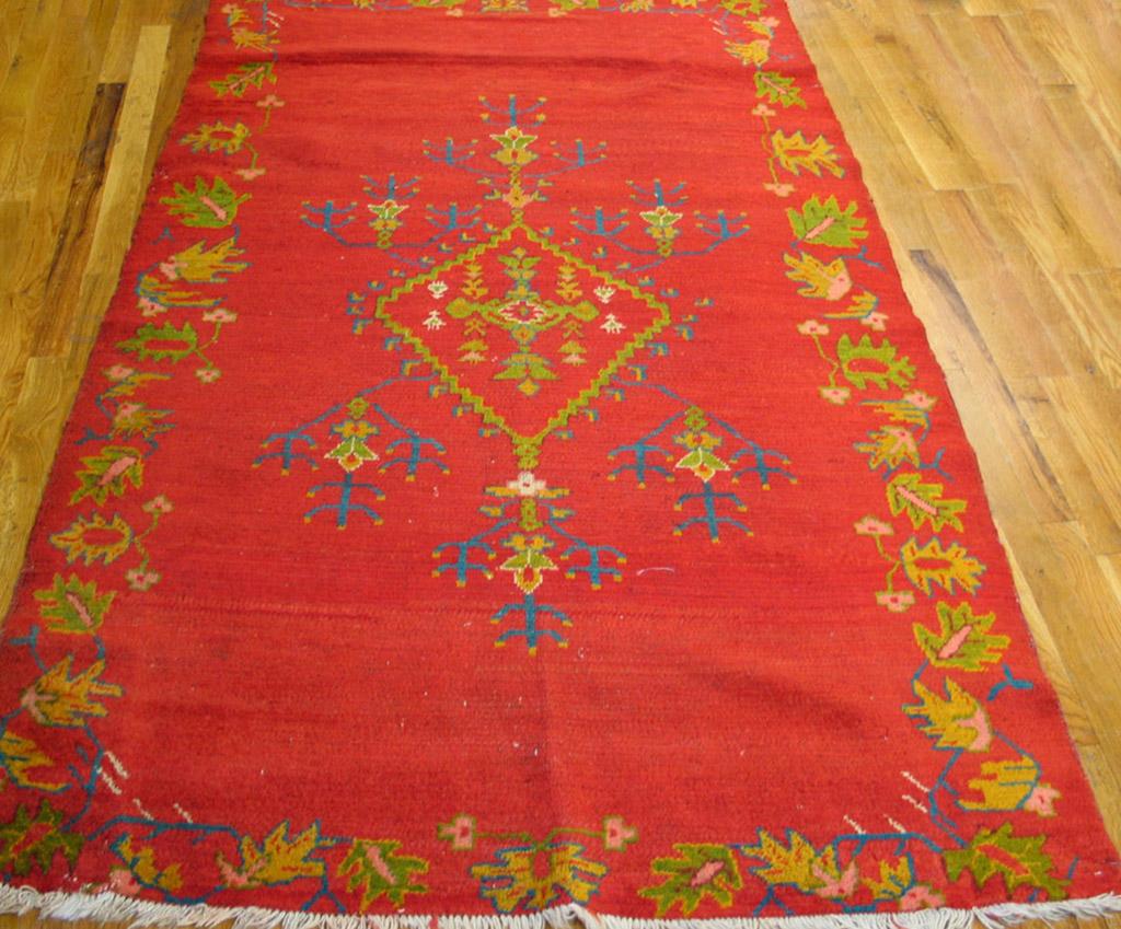 The saturated red open field bleeds over into an outlined border of yellow and green leaves. An open stepped lozenge medallion contains tiny flowers and sprouts six triple chandelier dark blue flowers. Although this rug dates circa 1910, the
