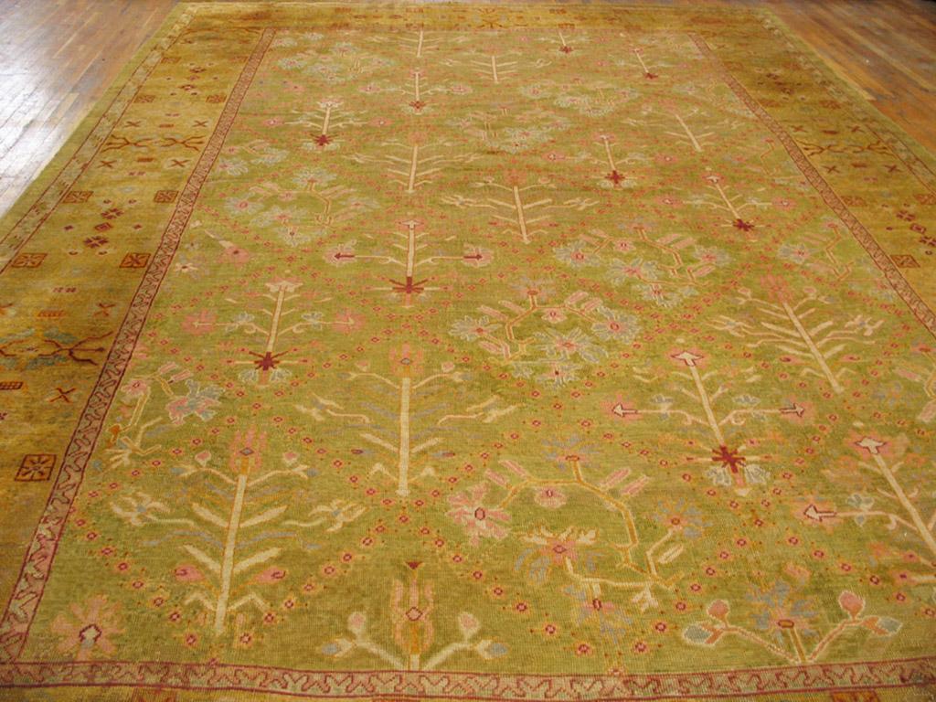 The popularity of Persian lattice and flower carpets led Oushak workshops to create their own variants. The grassy green ground displays various thin, attenuated flowers in off white and light blue, within a gold geometric floral border. Oushak