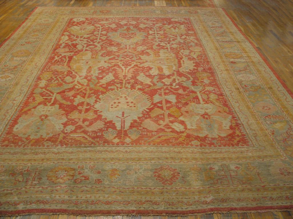 Coral red background antique Oushak rug 12'0