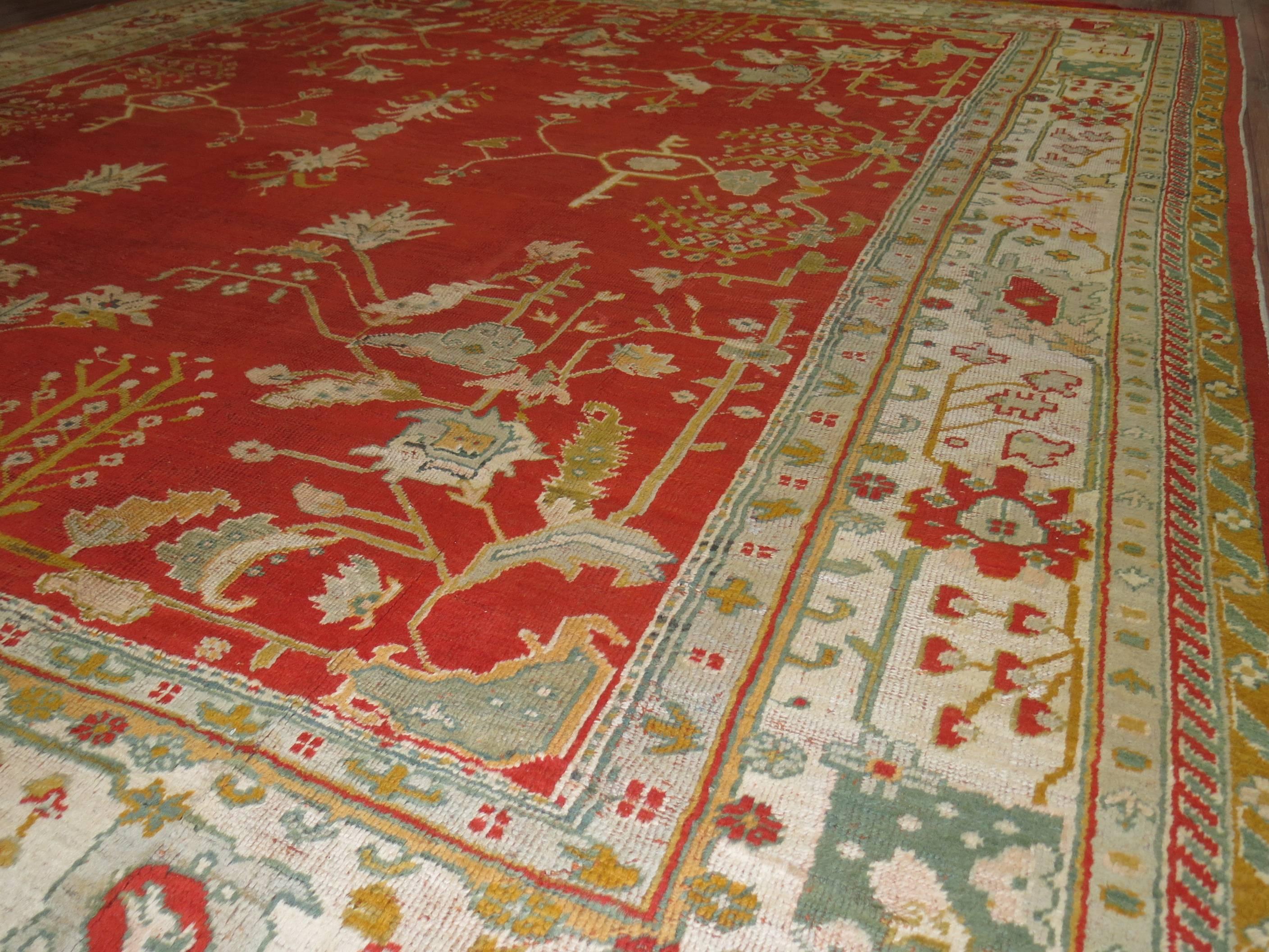 A colorful antique early 20th century Turkish Oushak rug in predominant bright orangy/red field and fresh ivory colored border. 

11'11'' x 13'9''

Antique Turkish Oushak rugs have been woven in Western Turkey since the beginning of the Ottoman