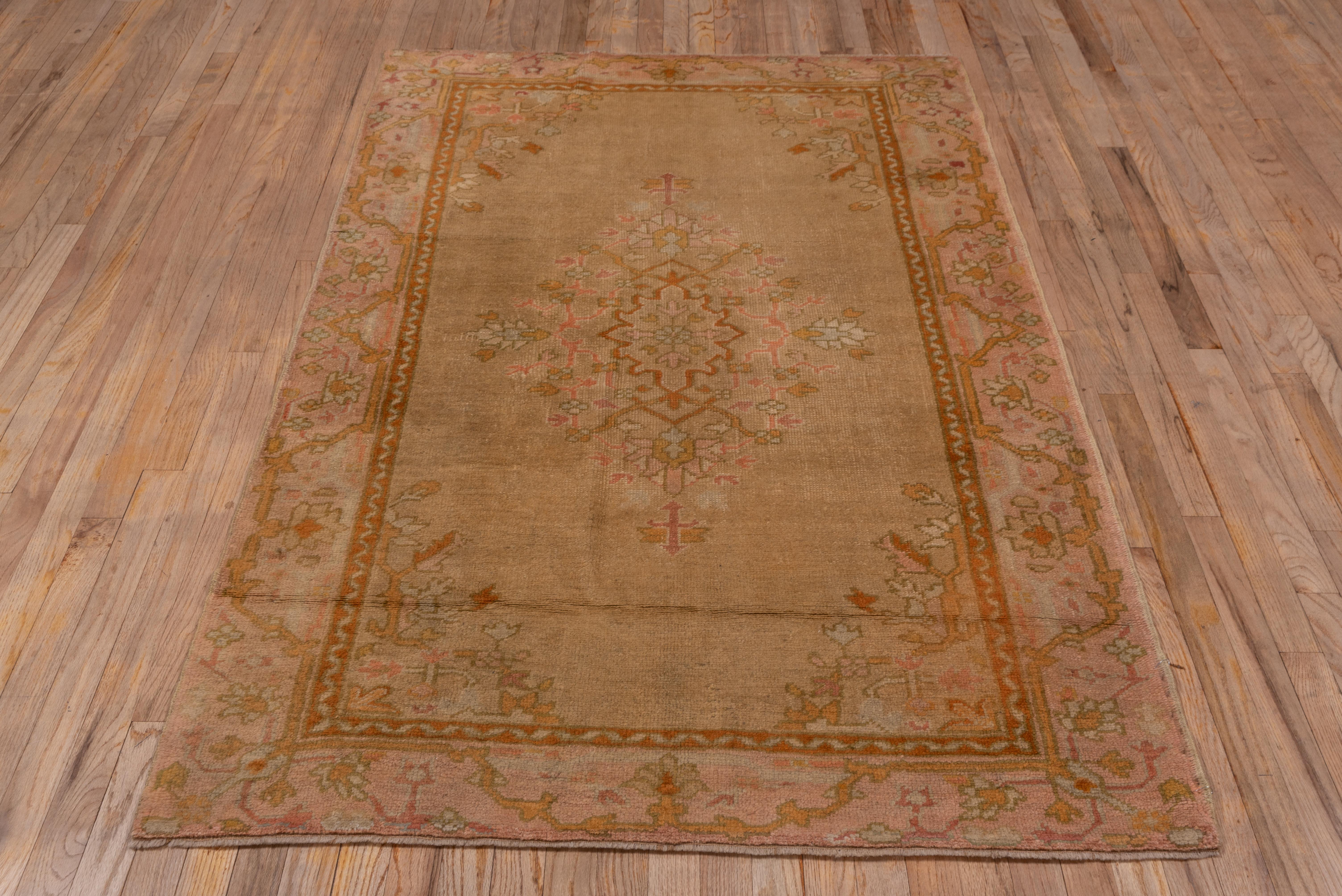 This western Turkish workshop rug shows a rust and goldenrod detailed ragged and palmette layered medallion on the golden beige open ground with leaf and stem corners. The tonally en suite border displays a stretched meander and palmettes.