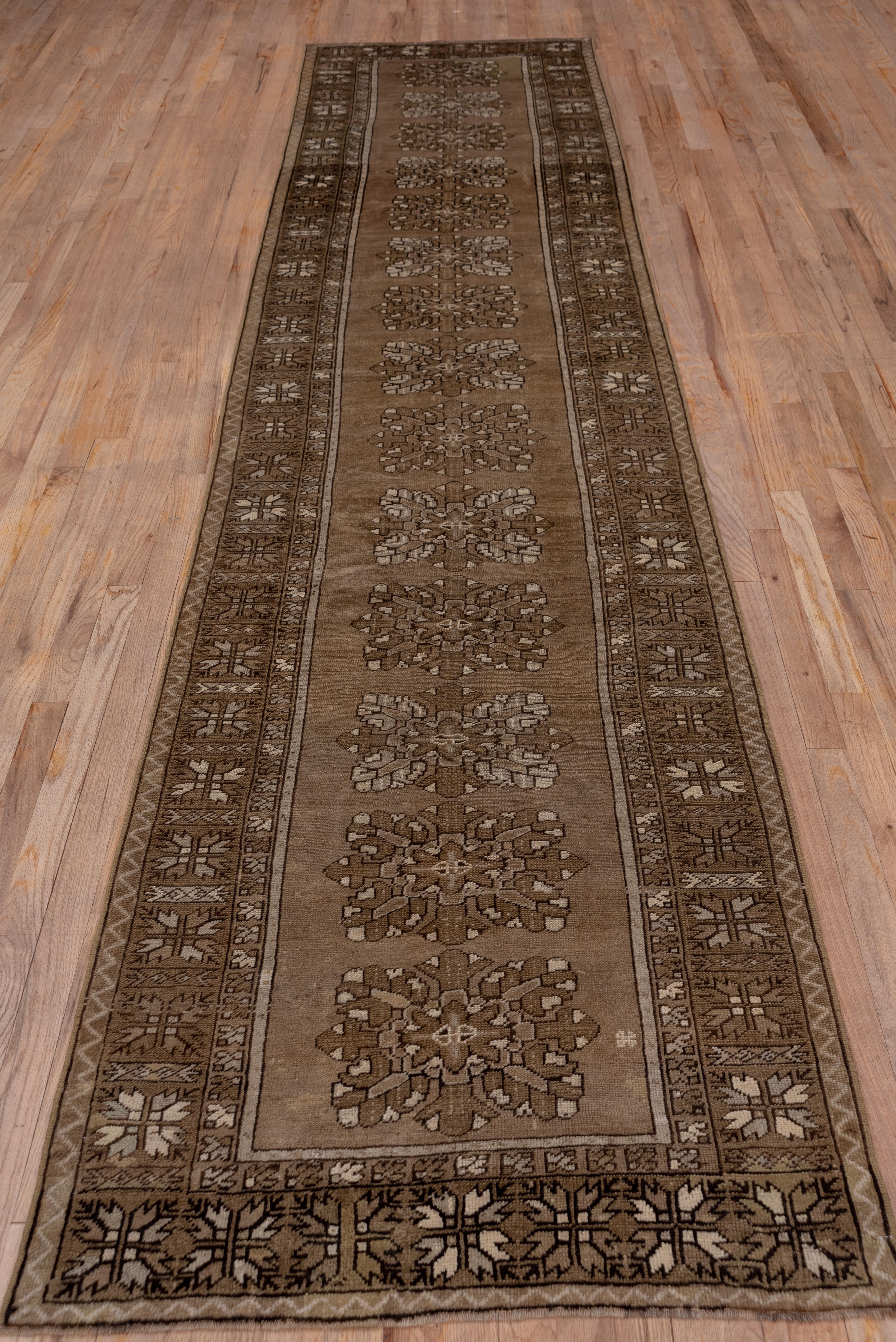 The camel-tone field displays a column of floating layered octofoil rosettes within a green border of four bud square star modules characteristic of certain central Anatolian Konya rugs. The handle is floppy and pliable.