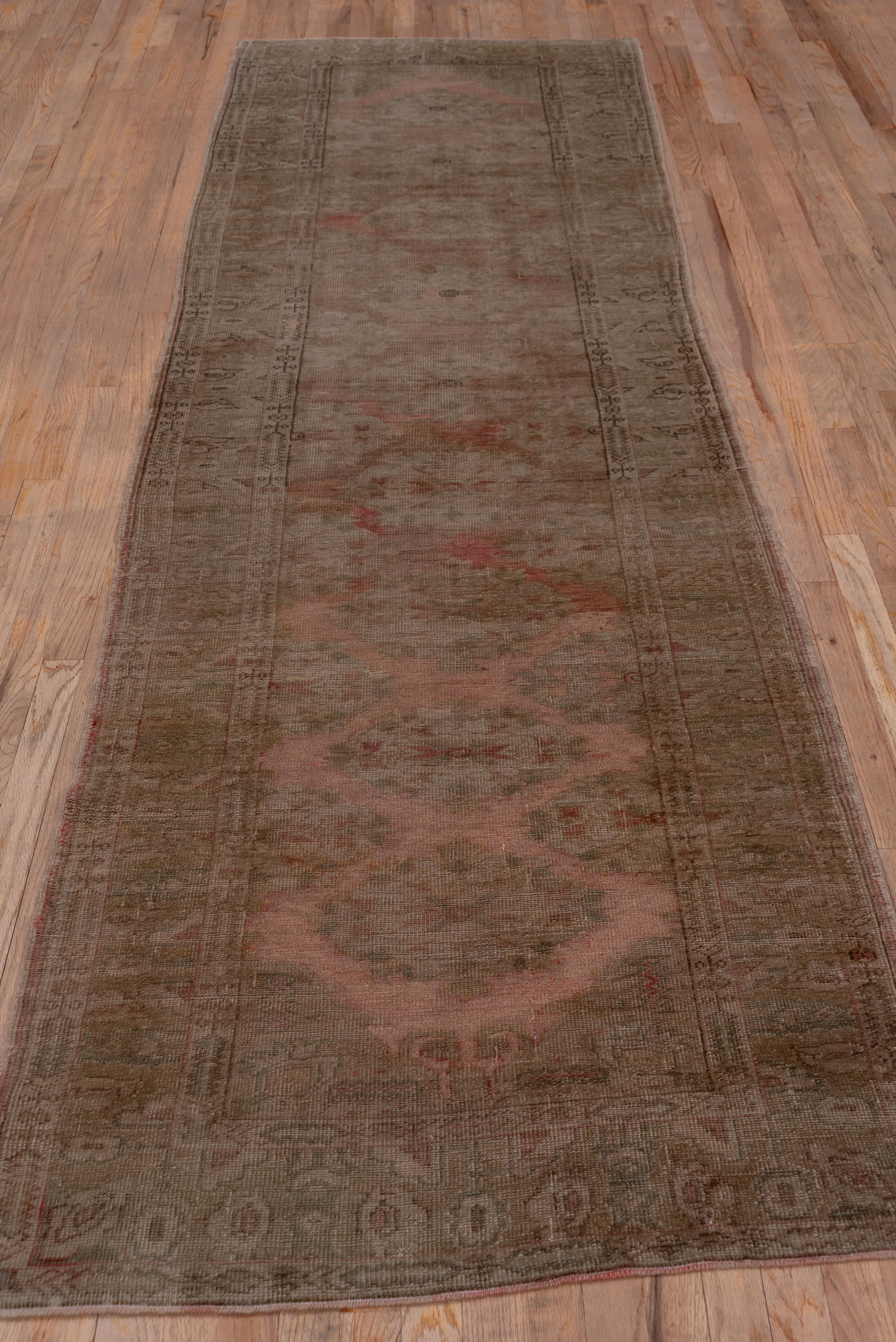 The light tan field of this west Turkish workshop runner displays a symmetric palmette pattern while the main border shows a naive leaf pattern. The condition is erratically low and lower. Sections of the minor borders and other details are rendered