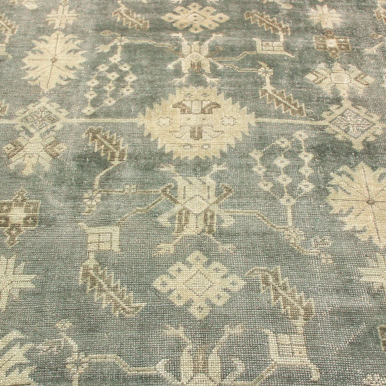 Hand knotted in Turkey originating between 1870-1880, this antique Oushak wool rug features a distinguished, rare colorway of stone blue with notes of tan and grey in the field and border, presenting an entirely unique presentation of its classical