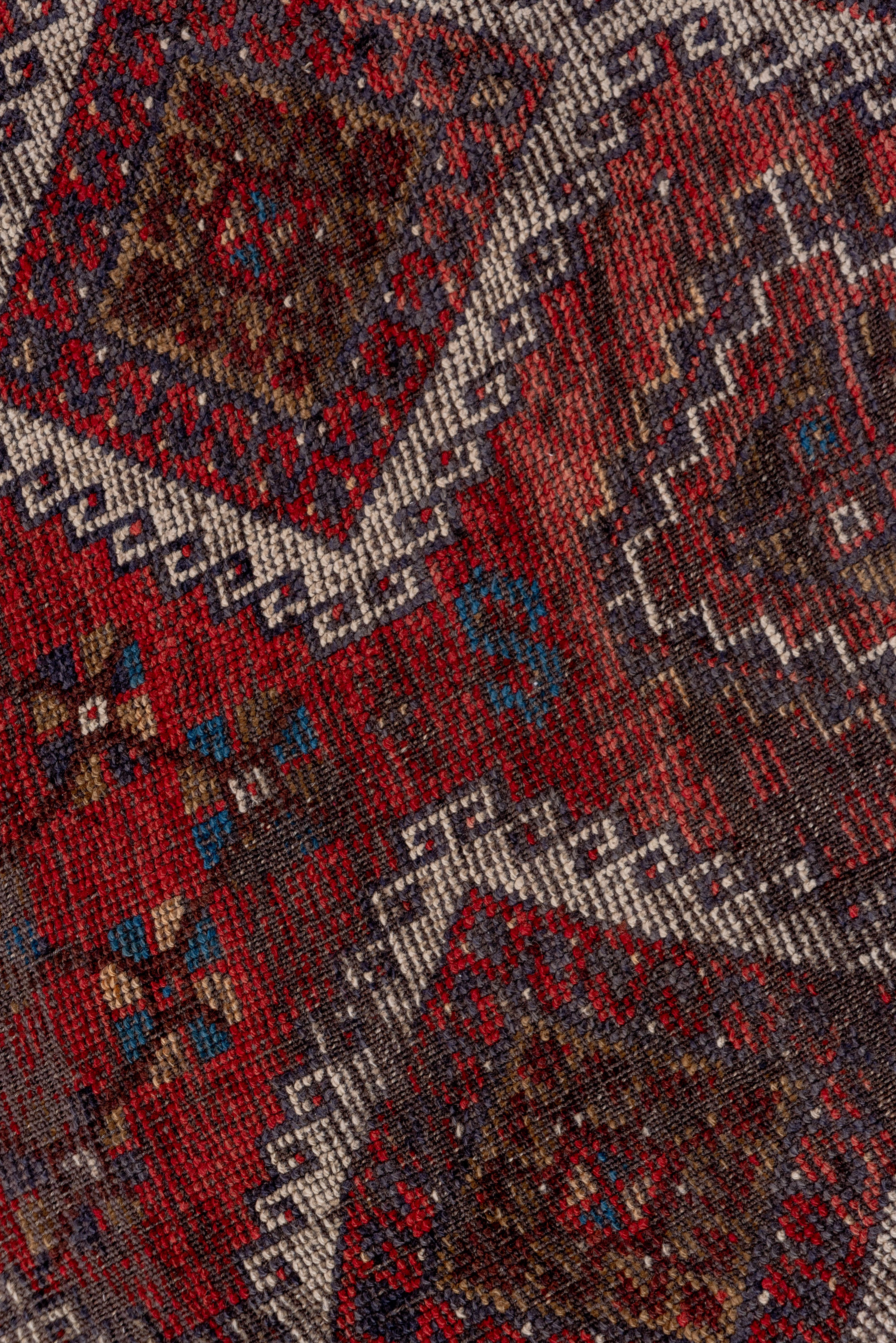An east Anatolian long rug with two columns of six attached, hooked ivory diamonds forming pole medallions on the red field, with rosette groups and nested, stepped diamonds as secondary devices. Narrow blue main border with meandering vine with