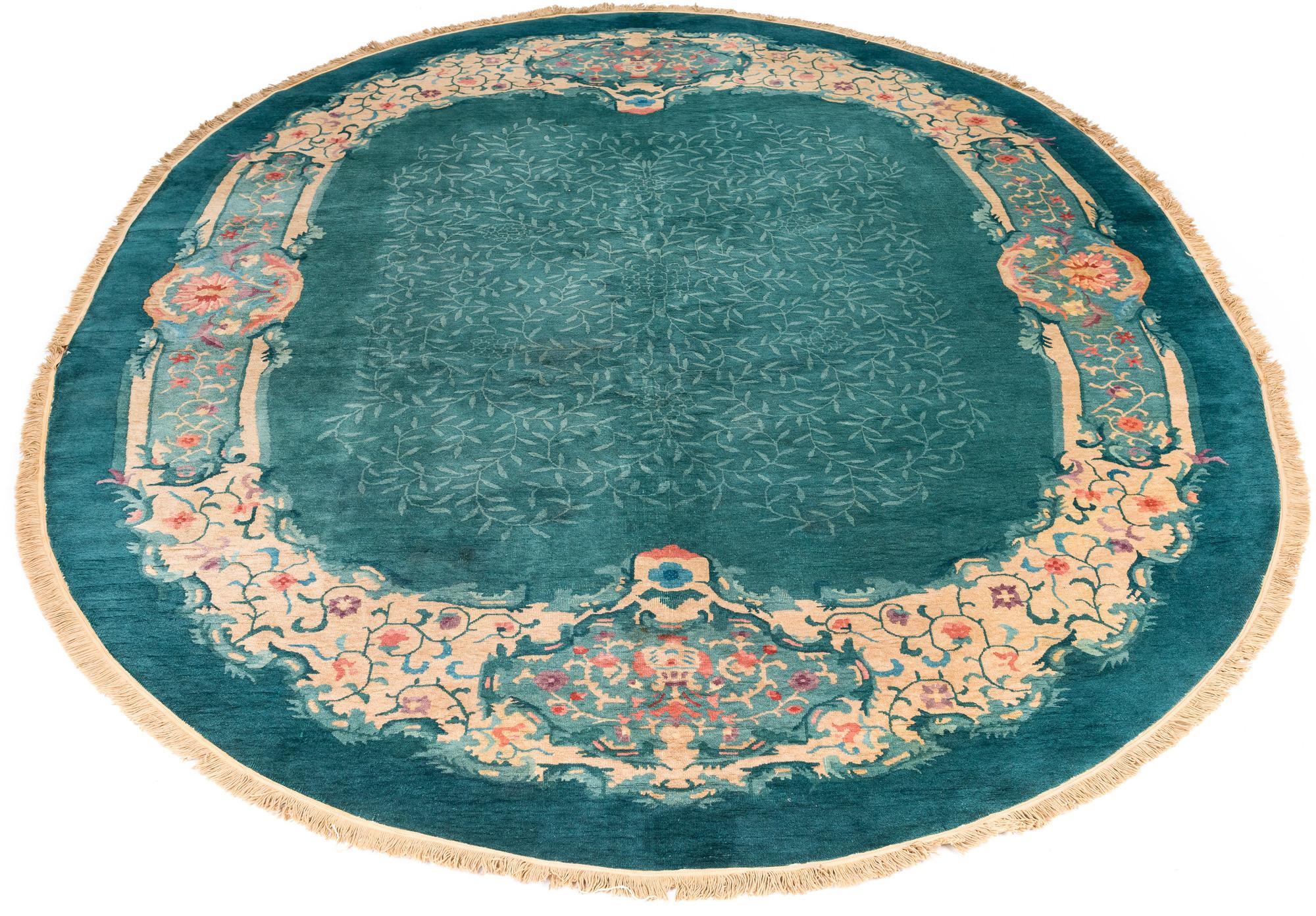 Antique Chinese oval rug was woven during a time when the more traditional designs began to fade and Art Deco designs were just starting to be produced. The green turquoise field has lighter colored vines on the main field. The outer turquoise color