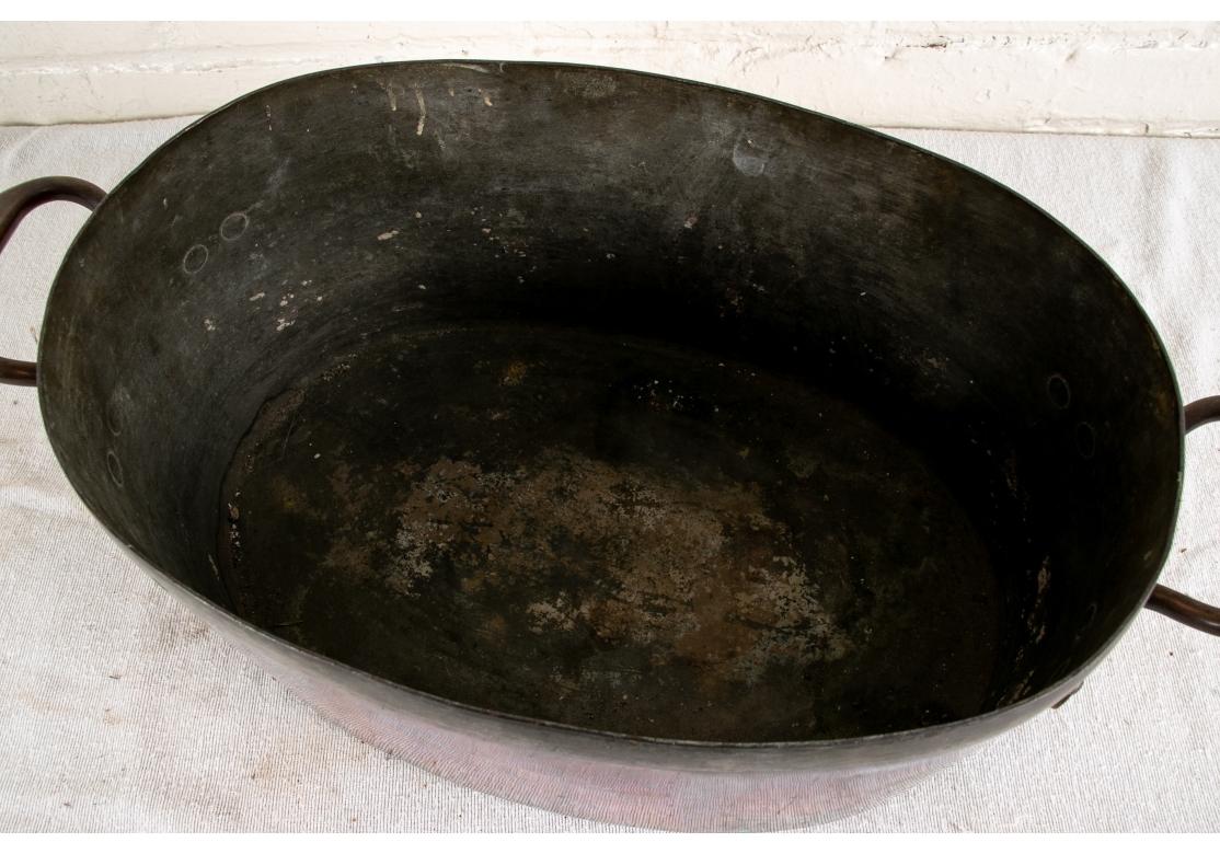 An authentic and heavy oval Copper Pot in all original antique condition. Tin lined with a tin coated rim and twin handles. 

L. 21