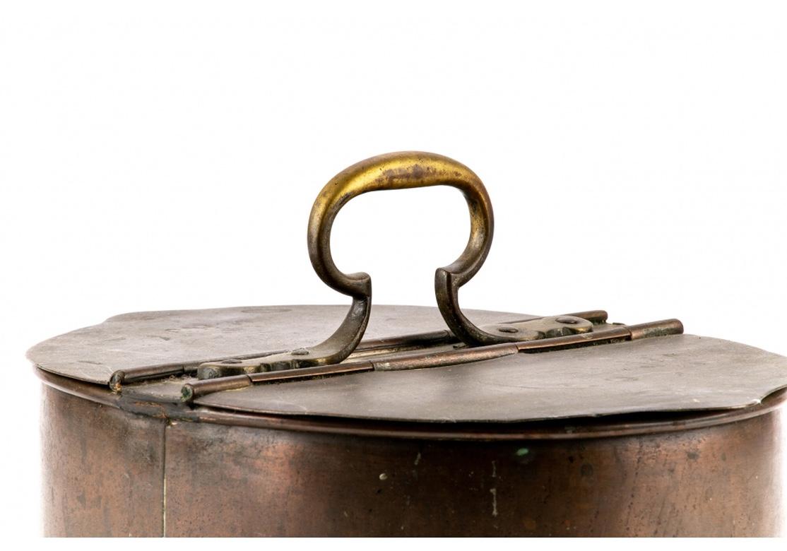 An antique copper vessel in all original condition with two divided lidded compartments, possibly a tinder box. With shaped double hinged lids, and an upright brass center carry handle. Engraved initials on one lid read, “M.H.J.”
Measures: Length