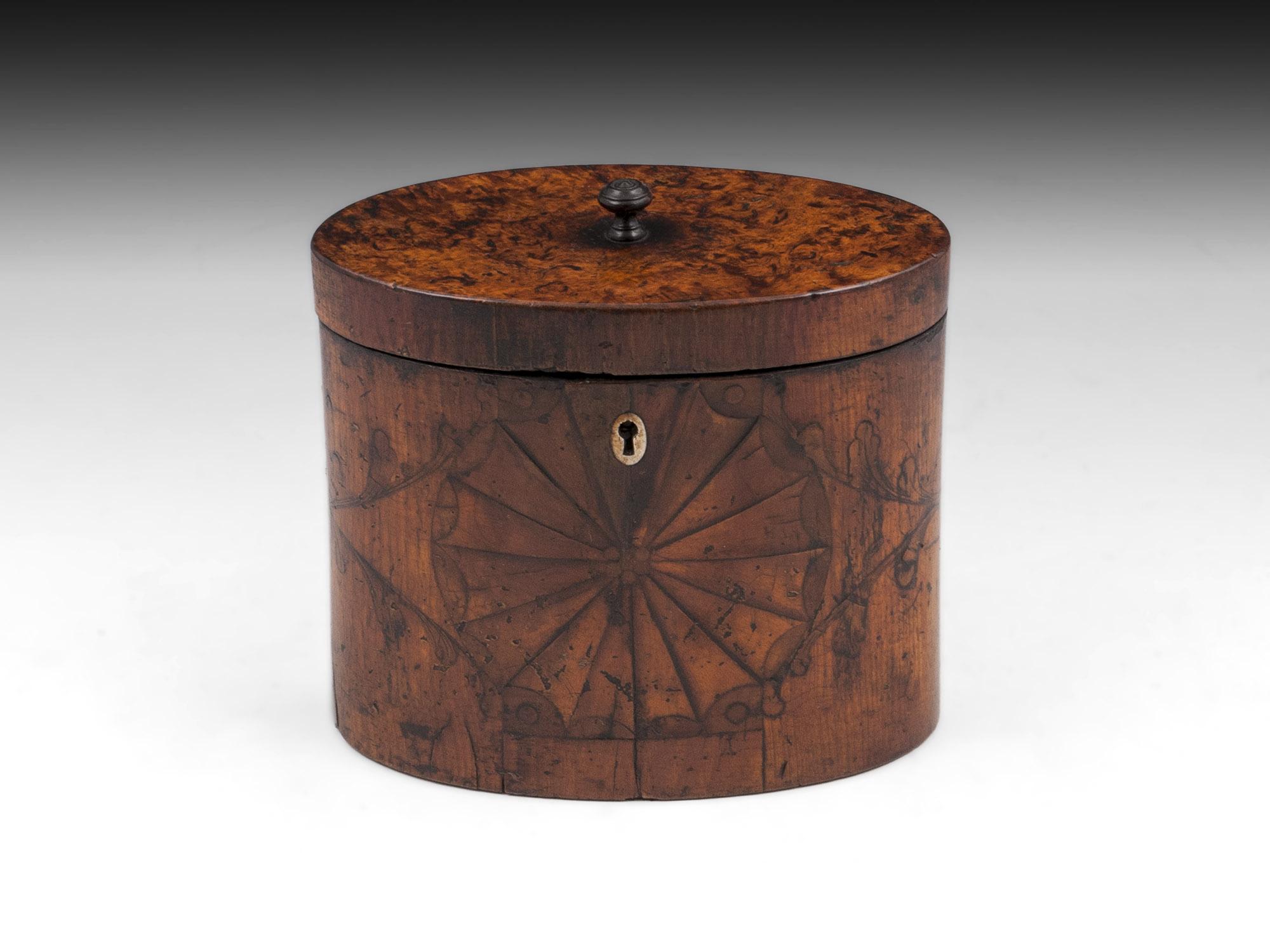 Antique oval satinwood tea caddy with unusual burr elm top with a turned handle. The front and back have wonderful batwing inlays connected by symmetrical florals with the front having a oval shaped bone escutcheon. 

The interior features traces