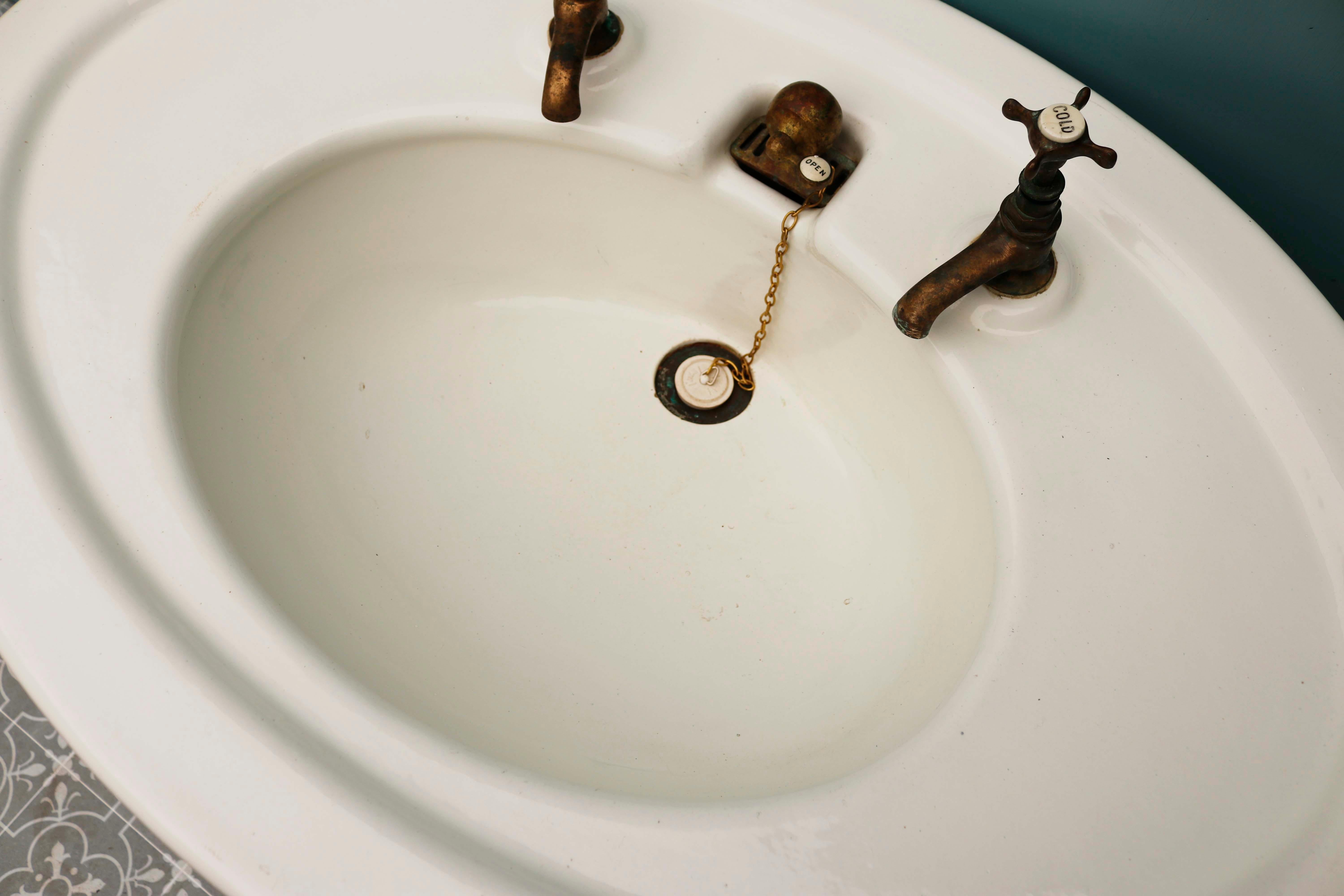 Antique oval shaped pedestal sink. A quaint 1920s stoneware sink which retains its original enamel coating and taps.
 