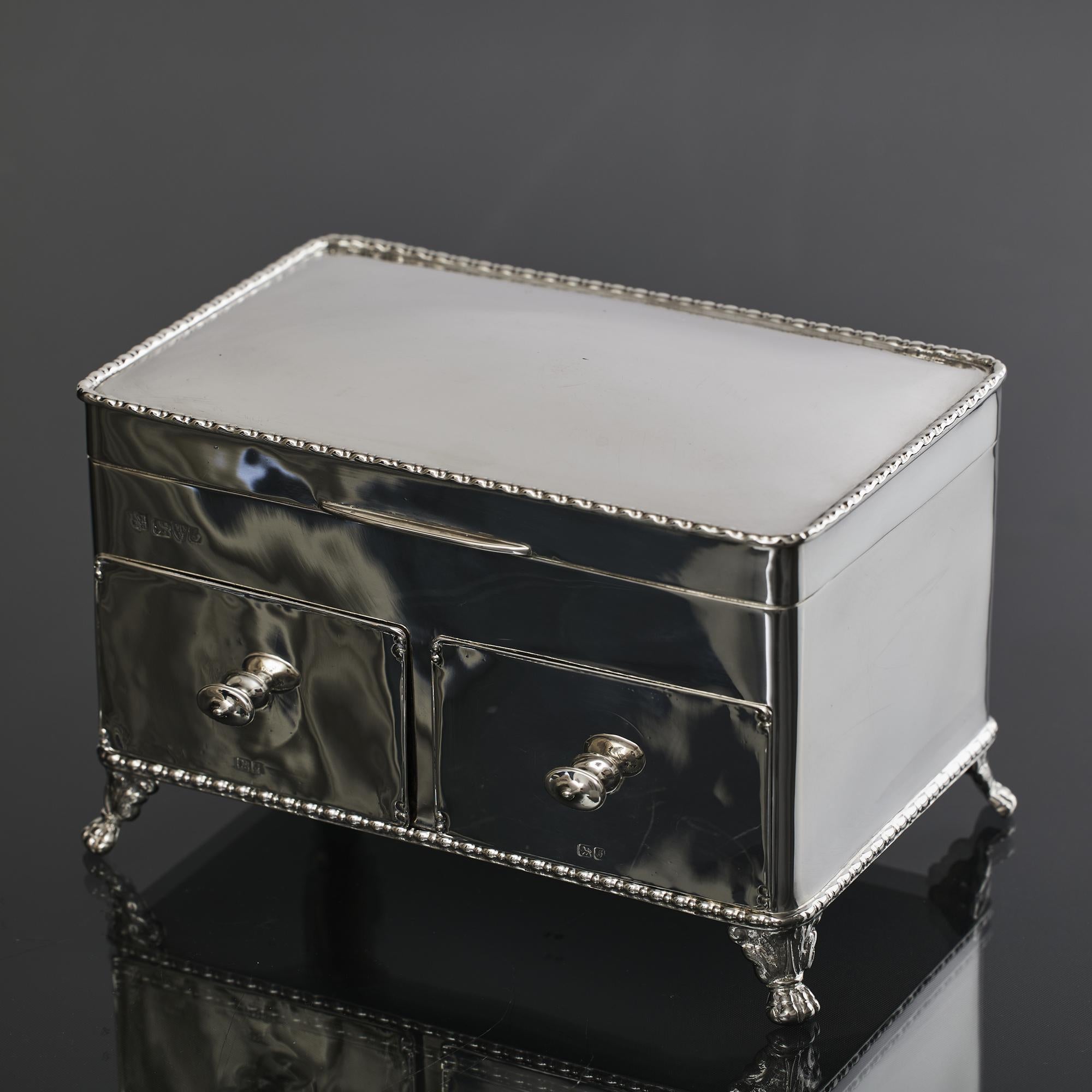 Handmade, late-Edwardian-era antique silver jewel box mounted on four leaf-and-claw supports and featuring two silver-fronted, pull-out wooden drawers and a gilt-lined hinged cover.
 
 The tray under the cover is lined in its original cream silk and