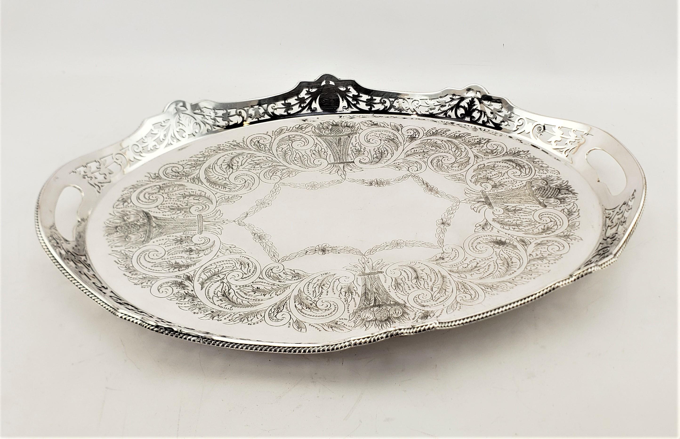 This antique silver plated and footed gallery serving tray is hallmarked by an unknown maker, and presumed to have originated from England and date to approximately 1920 and done in a Victorian style. This large tray is oval with an serpentine