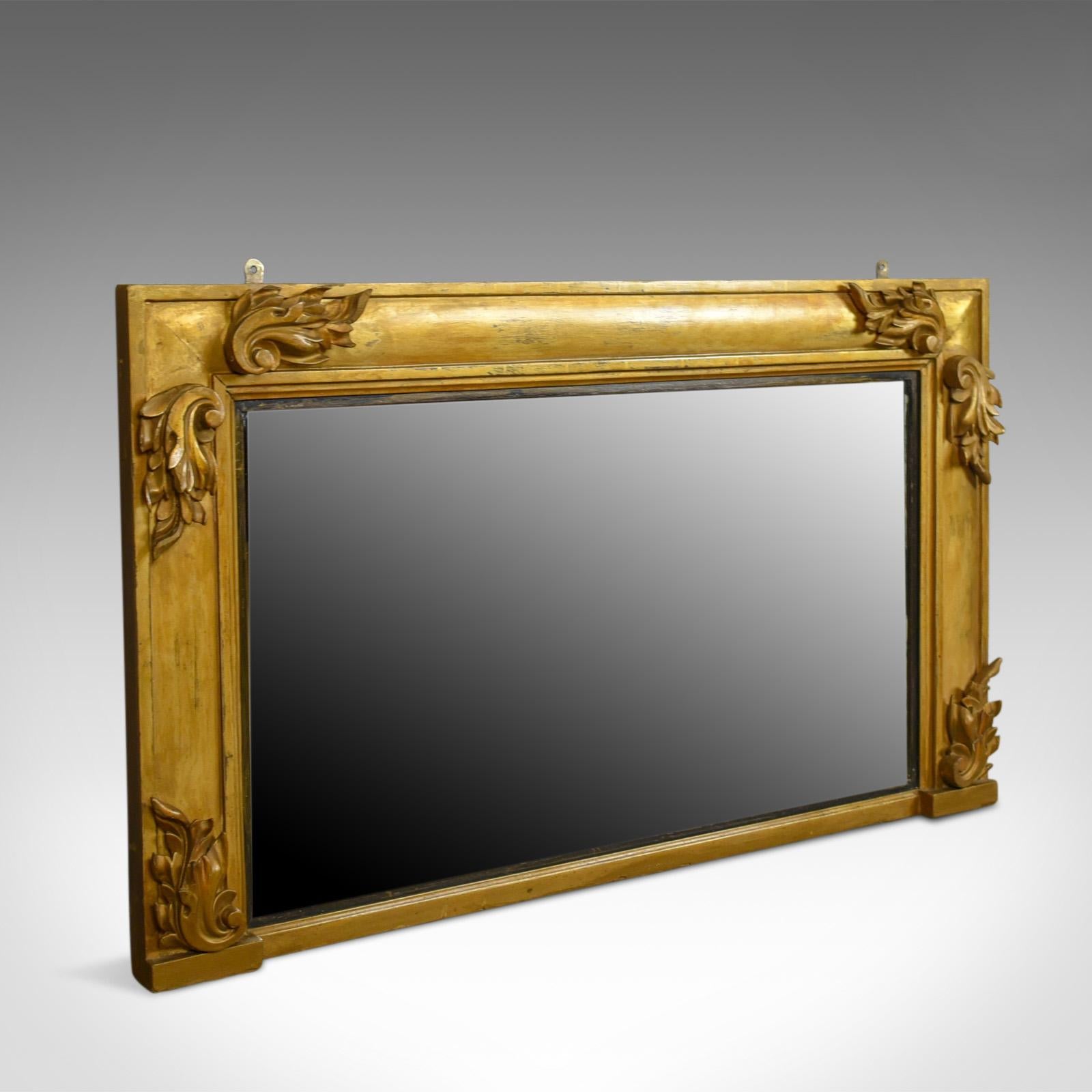 This is an antique overmantel mirror, an English, Georgian wall mirror in giltwood and gesso frame dating to circa 1800.

Attractive golden tones in the giltwood frame
Three-quarter, broad cushion moulding 
Standing upon a breakfront