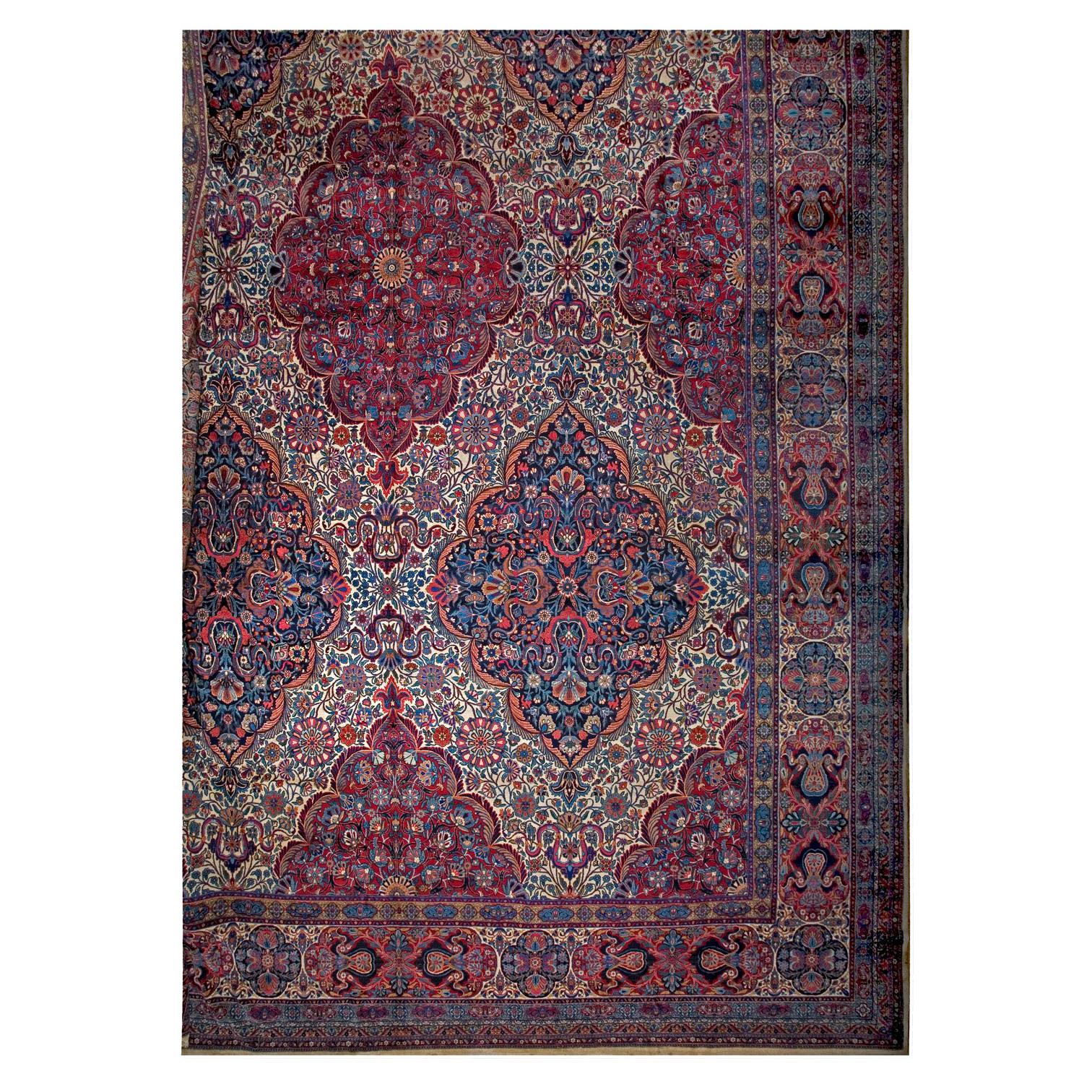 Antigua alfombra persa de Kirman Lavar con flores azules, c. 1910-1920