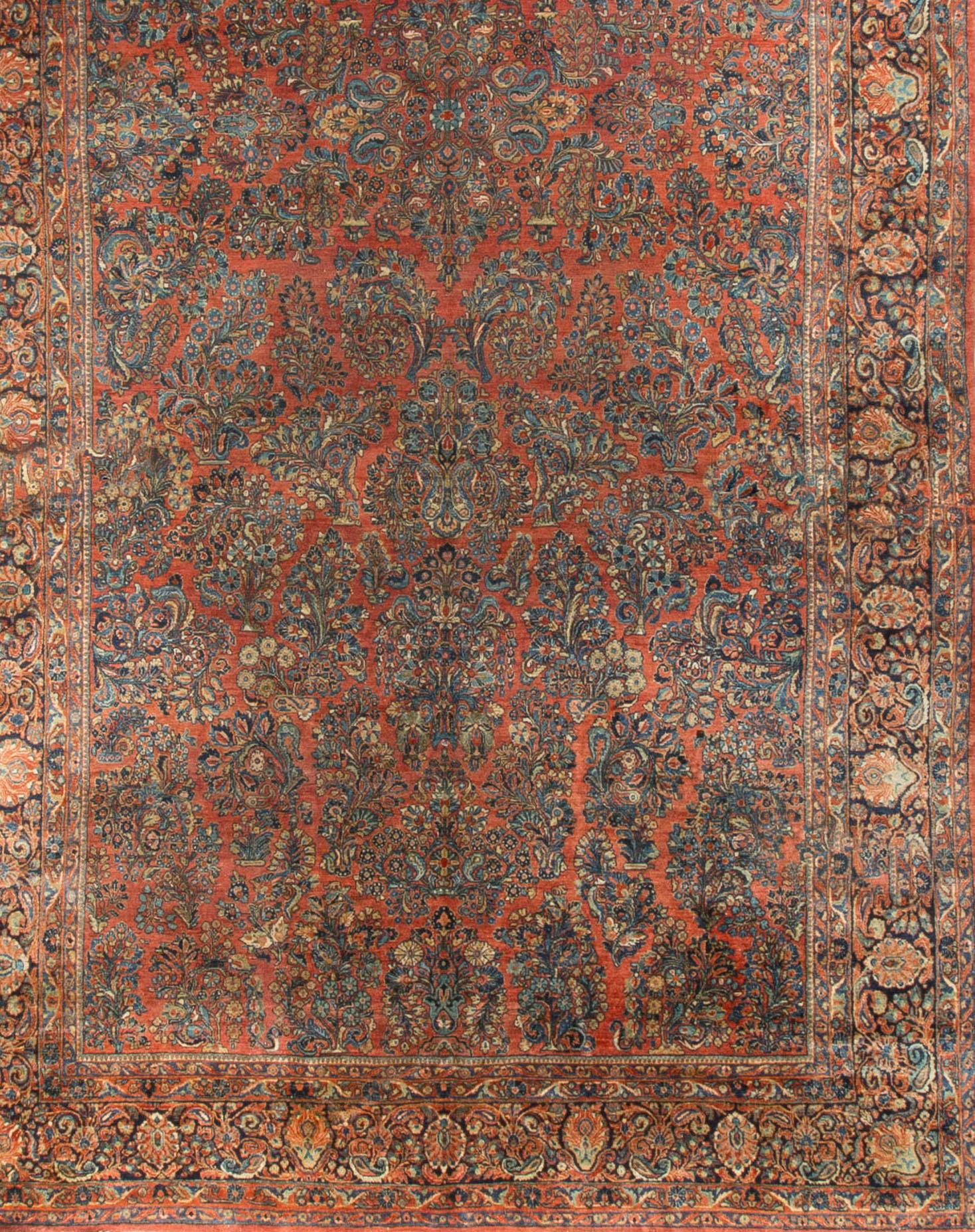 An antique Sarouk rug on a blue ground with a red entwined scrolling vine filled with foliate designs, enclosed by a navy border repeating the theme. Size: 10' x 21'6.
 