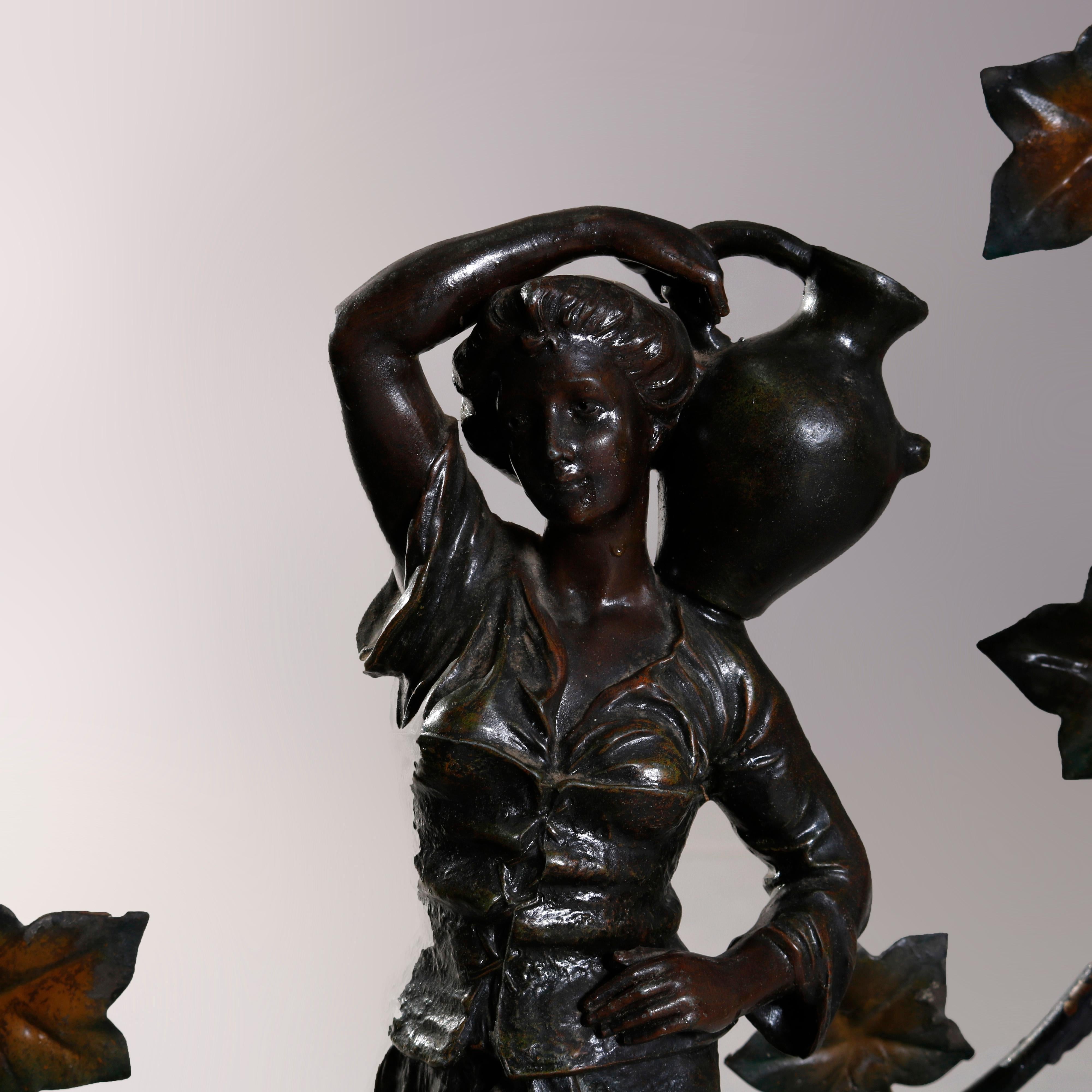 An oversized antique figural newel post lamp offers bronzed cast metal young woman carrying a water vessel in countryside setting with lamb at her feet, sculpture is haloed by grape vine with sockets, circa 1900

Measures: 33.25